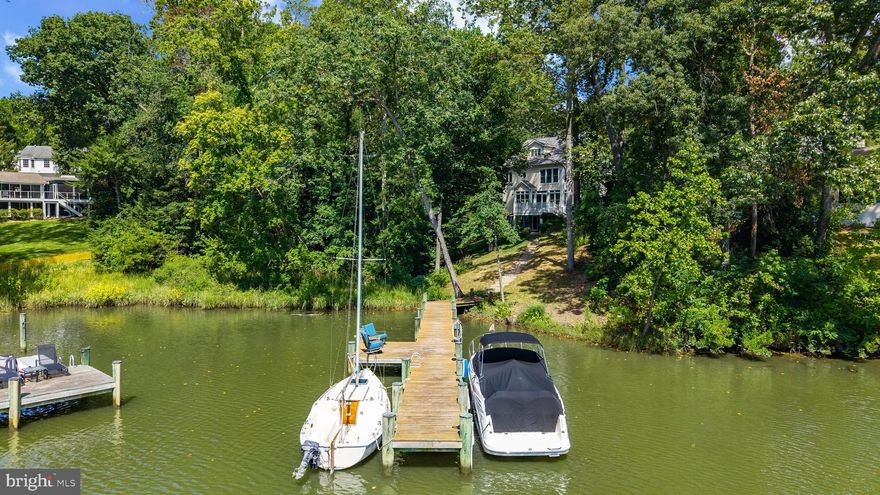 Nestled amongst the trees in the amenities rich Annapolis Roads community this 4 bedroom, 4.5 bath with 3,400 sq ft of living space has everything needed in a waterfront home! Discover the ultimate waterfront lifestyle with your own private pier on Lake Ogleton featuring 4’ MLW —providing seamless access to the Lake or out to the Chesapeake Bay for sailing, fishing, crabbing, or simply enjoying sunset cruises. Whether you’re an avid boater or just love the tranquility of the water, this property offers the best of both worlds. Inside, thoughtful details abound. The main level features a beautifully appointed kitchen and family room, enhanced with custom trim and crown molding, that opens onto a waterside deck—perfect for hosting gatherings or simply soaking in the views. Upstairs, the elegant primary suite offers water views, an elegant fireplace and a recently remodeled luxurious bath that feels like a spa retreat. Additional remodeled bathrooms throughout the home combine modern style with comfort. The versatile walk-out lower level expands your living space and could easily serve as a 5th bedroom suite, complete with full bath and wet bar—ideal for guests, multi-generational living, or casual entertaining after a day on the water. Set on a nature lover’s lot with lush plantings, the outdoor spaces invite you to relax in privacy while surrounded by beauty. Beyond your backyard, the community offers amenities that enrich the lifestyle: a Bayfront overlook with pavilion where neighbors gather, a playground, and scenic walking trails.  Located just minutes from downtown Annapolis and Eastport which offers the perfect balance of small-town charm and big world sophistication. Traveling or commuting is just as convenient by easily accessing Rt. 50 and 97 which provides direct access to Baltimore, BWI, Ft. Meade/NSA and Washington, DC., or head over the Bay Bridge to the Eastern Shore for a quick beach vacation. Welcome Home!