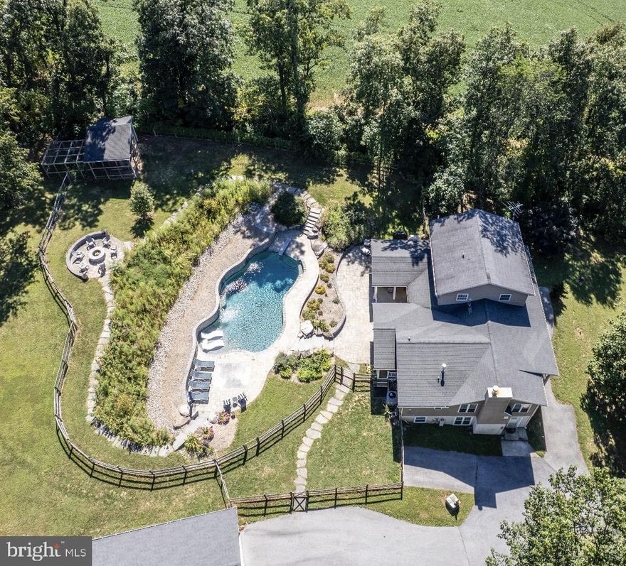 Incredible one of a kind estate! 5 bedroom 5 1/2 bath colonial style home with one of the nicest yards and pools in the area. The owners designed this home to entertain inside and out along with ease of living.  The main level has an open concept with recessed lighting throughout featuring a beautiful kitchen with stone counters, tiled flooring, large walk-in pantry, tiled splash and breakfast area that is open to the vaulted great room with wood flooring, kitchenette with stone counter and a tiled full bath. The kitchen is also open to  the cozy living room by a custom wood eating area and opens to a bright formal dining room along with a tiled half bath and a tiled mudroom to the rear yard/pool area. The main level also features the second primary bedroom with LVP flooring, walk-in closet with laundry and private tiled full bath. The upper level features the primary bedroom with LVP flooring, crown molding, private tiled full bath and private composite balcony. This level also has 2 other bedrooms, tiled hall full bath and a laundry area. The extensive lower level with recessed lighting throughout features a huge recreation room with high end fireplace wrapped in stone along with an exercise area, a media room with projector and movie screen, a custom home office with 3 work stations and built-in cabinetry, a full bath with marble flooring, a bedroom, laundry hookup and a utility area with storage. The exterior is absolutely amazing featuring a large covered patio with 2 ceiling fans, a composite rear covered porch, a huge composite covered front porch, large freeform patio backed by the stone retaining wall leading up the curving stone stairs to the custom heated saltwater pool complete with Pebble Tec finish, custom lighting, deep end with diving board, in pool lounging area, 3 waterfalls, hardscape and additional patio area. From the pool you can take the stone stairs on either side that both lead up to stone paths framing the wildflower meadow ending at the custom fire pit area. The owners have added fencing to isolate the pool area along with a side yard, small rear yard and large rear yard with vehicle gates. The oversized detached two car garage includes storage, electric and hides the pool equipment. There is an outbuilding that was used as a chicken coup the owner planned to convert to a pool house and storage along with a finished "tree house" with windows, locking door, futon and tv. The location is private and secluded offering trails through the wooded area in the rear however is only a short drive to the town of Manchester and offers easy commutes to Baltimore, Hanover PA, Westminster and many other locations. *****Aerial photos are from 09/2025*****