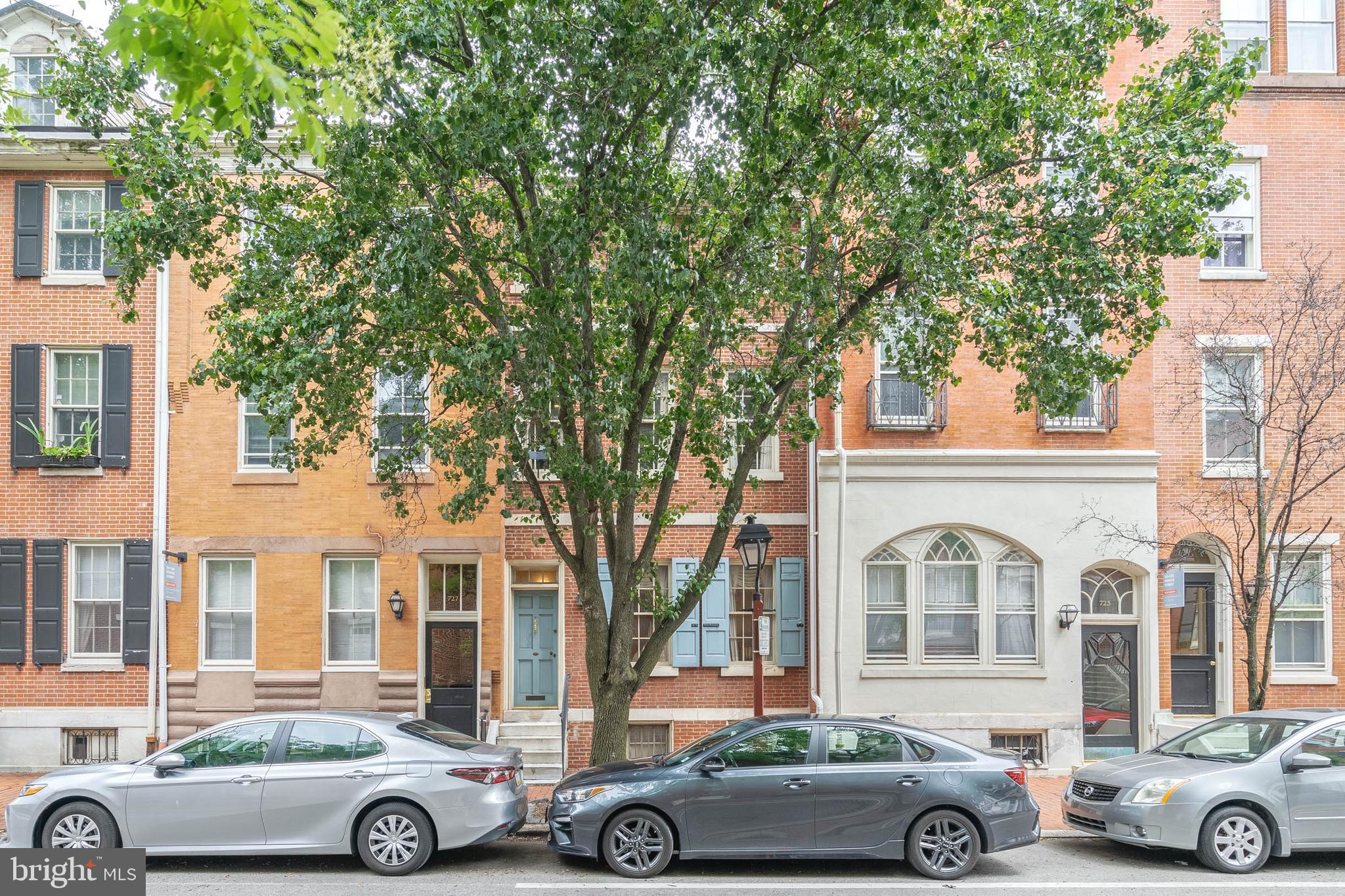 Prominently standing as a testament to Philadelphia's storied history dating back to 1803, 725 Spruce St is a large 3.5-story home offering 4 bedrooms + 2 dormer-bedrooms, 3.5 bathrooms, an idyllic private courtyard/GARDEN with 2-CAR PARKING, and a street-to-street lot sat in the heart of vibrant Society Hill. Its rich original character is waiting to be combined with modern updates to create a one-of-a-kind forever home. The towering front exterior displays classic curb appeal in its red brick facade and powder blue shutters. Inside, you're welcomed by a foyer and coat closet. Hardwood floors extend across the expansive, open main level, while crown molding trims the soaring ceilings. A marble fireplace anchors the front living area, where a pair of tall windows provide natural light. The dining area is made for entertaining with space to accommodate a table for 8+. Past the staircase and a powder room, the large kitchen has a full suite of appliances, bright windows, and a breakfast nook. One of the home's highlights is surely the serene private courtyard that acts as a peaceful escape from the city's hustle. It has a large paver section for barbecues and al fresco dining, along with a secure, oversized 2-car parking pad. Up on the second, the hotel-like primary suite at the front has 3 tall windows, a fireplace, a walk-in closet, and an attached full bathroom. Down the hall is a study with built-ins and another bedroom suite. The third level has two more bedrooms flanking the third full bathroom. A pair of dormer bedrooms and a closet are on the top level. Completing the home is a huge basement where you'll find the laundry and tons of storage. 725 Spruce St's utilities include dual-zone HVAC and 2 gas water heaters. In addition to everything inside, this highly sought-after Washington Square West location earns a Walk Score of 97! It's only a few blocks from Center City, yet it has a small neighborhood feel. Top-rated restaurants, friendly local shops, and lively entertainment fill the surrounding streets. You can spread out at sprawling Washington Square Park or get active at Seger Park, both nearby. Pennsylvania Hospital is steps away, Jefferson Hospital is close, and there's easy access to public transit, I-95, and South Jersey. Schedule your tour today!