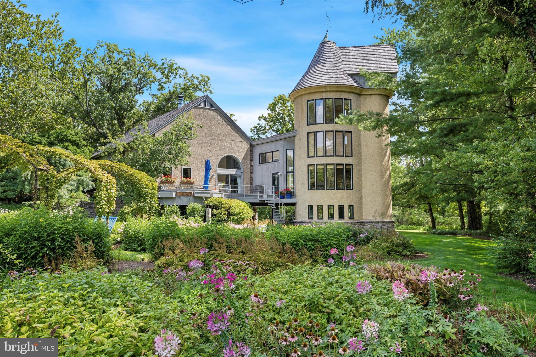 Nestled on a tranquil cul-de-sac and approached via a dramatic, long driveway, Walmere Manor is a stunning circa 1801 stone bank barn, complete with a silo, set on nearly 6 acres in Blue Bell’s Whitpain Township. This impeccable estate is a true oasis, surrounded by pristine landscaping and lush gardens that lead to a serene one-acre pond, complete with a dock and fountain. Originally transformed into a modern residence in 1985, the home’s character shines through its preserved interior stone walls, exposed wood beams, and original wide plank hardwood flooring in the master bedroom. The property was further expanded in 1990 with the conversion of the original silo into additional living space, offering breathtaking views of the surrounding woods and pastures. As you step inside through the vintage front door, complete with its own skeleton key, you’ll be greeted by gorgeous hardwood floors and original exposed wood beams that add to the home's charm. A cozy office is just a few steps up to your right, while a convenient half bath and the first-floor master wing lie to your left. The master suite is a private retreat, featuring a separate laundry area, full bath with soaking tub, stall shower, double vanity, and a private balcony with stunning views to wake up to each morning. A spiral staircase outside the master suite leads to the second floor, home to two generously sized bedrooms with large closets and a full hall bath. The main level boasts a living room with extraordinarily high ceilings and a full original stone wall, adjacent to sliding glass doors that open to a grand two-tier deck with sweeping views of the gardens. The galley kitchen, with its quaint breakfast nook, is bathed in natural light from windows and skylights, offering plenty of storage, a double wall oven, and stainless steel appliances. The converted silo, with its floor-to-ceiling windows, is a must-see—cozy yet elegant, it’s the perfect spot for relaxation. A spiral staircase in the silo leads to two additional levels, one housing a full bath and the other a versatile bonus area ideal for an office space. The lower level, accessible from the oversized 3-car garage, offers two bonus areas perfect for additional storage or a workout room. With ample parking space in the driveway, this home is truly stunning, both inside and out. Every inch is thoughtfully appointed with unique decorative touches that make it both distinctive and welcoming. Located in the desirable Wissahickon School District, this historic home is a must-see. Schedule your tour today and experience the charm of Walmere Manor—a beautiful retreat that could be your new home.
