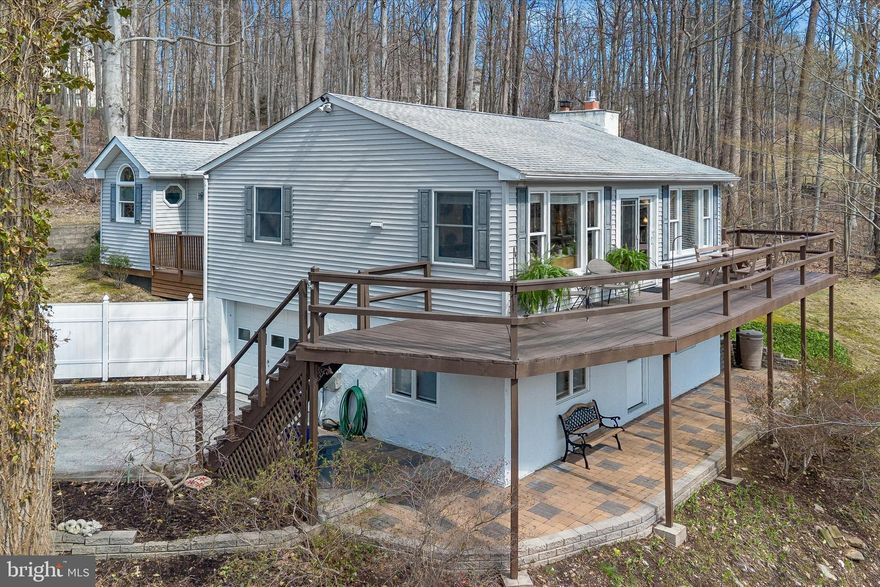 Down a lightly traveled road, through the woods, and overlooking the Buck Run stream is where you'll find your inviting, mountain-esque home on 2.5 acres. Bursting with warmth and charm, 50 Timacula will put your home search at ease. With trees for neighbors, you can imagine how serene it must be to gaze out through the large windows and into nature. Starting on the main floor, you'll first notice the natural light pouring in and highlighting an especially beautiful living space. The kitchen remodel is the star of the show with radiant floor heating, quartz countertop, tile backsplash, stainless steel appliances, gas cooking, and an abundance of cabinet space. Grab a seat in the sun at the dining table or cozy up by the stone fireplace. Travel through the hallway where you'll pass a bedroom and full bathroom, and into the massive primary suite with vaulted ceiling, its own balcony, walk-in closet/laundry combo, and a tasteful bathroom. Spiral down to the lower level and into the den which could easily be customized into whatever sort of space you desire. The 3rd bedroom is located on this level and could be perfect for guests or in-laws. Garage access is convenient, and storage is plentiful. If you enjoy spending time outside, you have two amazing options with the deck and patio which both stretch the length of the house! To summarize, this breathtaking property is a gem nestled in the countryside of Chester County. It's as simple as, put your money down and kick your feet up!
