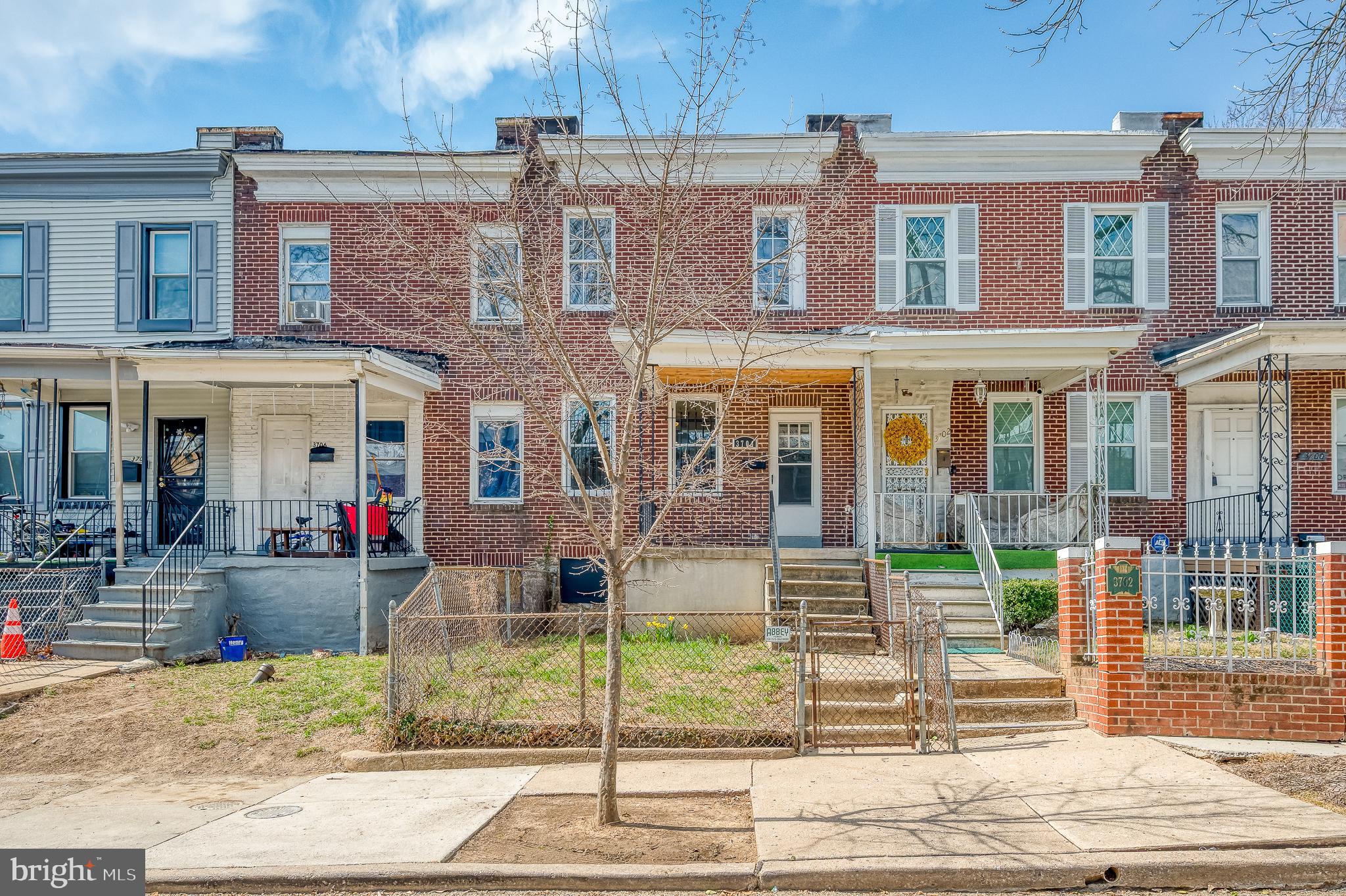 Newly Refreshed & Move-In Ready! This 3-bedroom, 1.5-bath traditional rowhome in Baltimore’s Central Park Heights community features a smart, functional layout and fresh interior updates throughout. A covered front porch and fenced front yard create a welcoming first impression. Inside, the main level showcases newly updated laminated flooring, recessed lighting, a ceiling fan, and a sleek wall-mounted electric fireplace that adds modern flair. The open-concept kitchen blends style and practicality with butcher block countertops, white cabinetry, stainless steel appliances, a tile backsplash, and a peninsula with pendant lighting and breakfast bar seating. The dining area is integrated into the kitchen space, offering a seamless layout for both casual meals and entertaining. A main-level powder room adds convenience. Upstairs, a hallway skylight brings in natural light. All three bedrooms feature laminated flooring, ceiling fans, and a neutral color palette. The full bath has been fully renovated with marble-style tile, modern fixtures, and an updated vanity with sconce lighting. The lower level includes a finished flex space ideal for a family room, home office, or gym, along with an unfinished laundry and utility area that provides extra storage and walkout access to the backyard. Outdoor highlights include a fenced yard, rear patio, private off-street parking with alley access, and additional street parking in the front. Blending comfort, updates, and everyday function, this refreshed home is a standout opportunity in a well-established Baltimore neighborhood.
