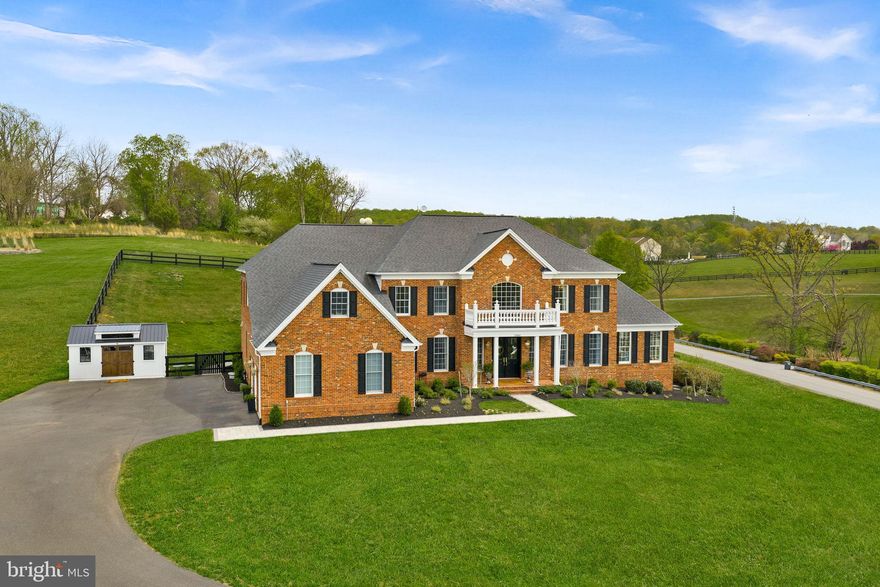 Welcome Home to this Refined Estate with Blue Ridge Mountain Views set on 3.06 acres in Waterford, Virginia. This exquisitely renovated estate offers more than 8,200 square feet of luxurious living, thoughtfully designed to capture both natural beauty and architectural presence.
A grand arrival begins with new double entry doors opening into a dramatic two-story foyer, where a striking double-sided curved staircase creates an unforgettable first impression. From this central vantage point, the home immediately reveals its scale and intentional design—framing direct views of the Blue Ridge Mountains through the front of the home, while also offering seamless sight-lines through to the family room and out to the backyard. Formal living and dining rooms gracefully flank the foyer, while a sun-drenched conservatory and expansive windows fill the home with natural light throughout the day.
At the heart of the home, the gourmet chef’s kitchen is both sophisticated and functional—anchored by an impressive 11-foot island with seating and appointed with a curated suite of Café appliances, including a French-door wall oven, built-in microwave, French-door refrigerator, a custom exterior-vented hood, and a 36-inch commercial-style gas range. The kitchen also features an expansive Breakfast Room area that easily accommodates a table for 12, as well as a built-in desk area that adds convenience for daily living. Designer lighting and hardware, marble tile and luxurious countertops complete the space, while the adjoining Sunroom and the Breakfast Area overlooks the grounds and opens to a new Trex deck, seamlessly connecting indoor and outdoor living and leading to a beautifully crafted flagstone patio.
The main level is completed by a 2-story family room, back stairwell to the upper level, private office, mudroom, and laundry room, as well as a beautifully appointed powder room, thoughtfully designed with elevated finishes to reflect the home’s cohesive sense of luxury.
Upstairs, the primary suite serves as a true private retreat, offering both scale and thoughtful design. The suite features a separate sitting area, a generously sized secondary walk-in closet (approximately 9' x 7') within the bedroom, and an exceptional primary dressing room accessed through the ensuite bath measuring approximately 24 feet by 10 feet—creating a boutique-style wardrobe experience rarely found in residential design. The spa-inspired bath is equally impressive, showcasing a freestanding soaking tub, dual vanities positioned opposite one another, two separate water closets, and a double walk-in shower—delivering a retreat-like experience within the home.
Three additional bedrooms and fully renovated ensuite bathrooms continue the home’s elevated design throughout the upper level.
The fully finished lower level, spanning approximately 2,600 square feet, offers exceptional flexibility for multigenerational living. This level features a second gourmet kitchen with a 10-foot island, expansive living and entertaining areas, a private suite with custom walk-in closet and ensuite bath, two additional bedrooms with shared full bath, storage, media room, and additional flexible spaces. Direct walk-up access provides seamless connection to the backyard.
Both kitchens are equipped with all new appliances, and the home includes two new sets of washers and dryers, enhancing convenience and functionality across both living levels.
Outdoors, enjoy over 3 acres of peaceful countryside, including a 1-acre fenced yard with a county-approved pool fence and gates, offering both privacy & future potential.
Located in a bucolic setting, this home offers a rare combination of tranquility, heritage, and modern luxury—with Blue Ridge Mountain views greeting you on arrival and the best of Western Loudoun living just moments away.

New: Hot Water Heater. 2 HVAC. Well Pump. Double Front Entry Doors. Hardscape. Workshop. Renovations throughout. Come See and Fall in Love!