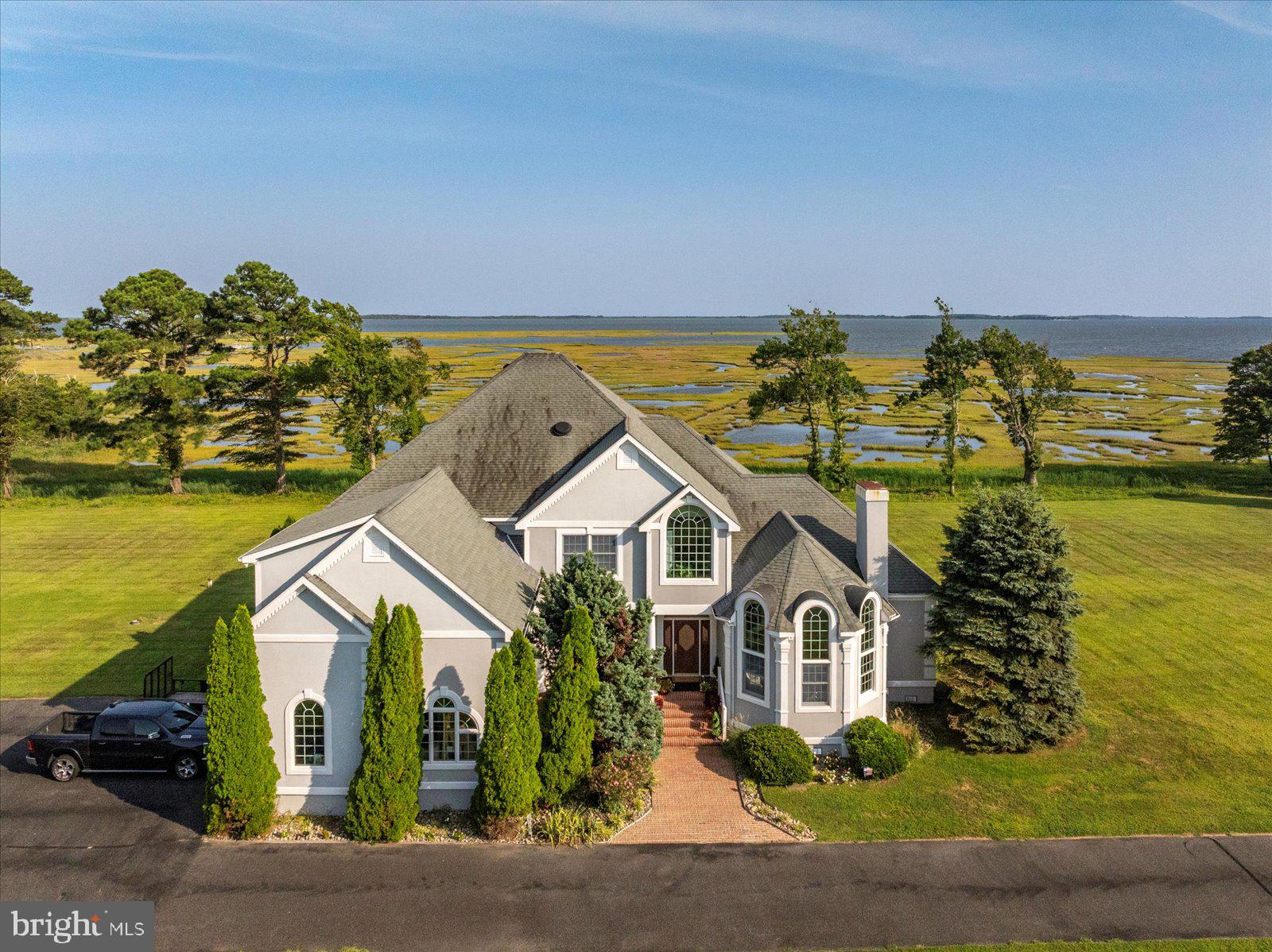 This recently remodeled 6,482 sq. ft. luxury estate offers breathtaking views, unmatched privacy, and access to the water with boat slip #3 in the community marina included. Nestled on over 2 acres, it combines elegance, space, and location—just minutes from Ocean City, golf, and all that Assateague Island has to offer. The home features a grand family room with soaring ceilings and a custom fireplace, a gourmet kitchen with granite counters, butler’s pantry, mini bar, two new refrigerators, and upgraded Spanish tile flooring. A spacious breakfast area, formal dining and living rooms provide the perfect flow for entertaining. The first-floor primary suite showcases water views and a spa-like bathroom with soaking tub, spa shower, imported tile, and custom finishes. Upstairs, you'll find four additional bedrooms, three fully renovated bathrooms, and a home theater/game room. Enjoy the outdoors from the expansive 40'x12' waterfront brick patio—ideal for dining and relaxing all overlooking the Assawoman bay. Recent upgrades include: full interior and exterior painting, bathroom remodels, kitchen floor, lighting, landscaping, and newer HVAC systems. This property offers exceptional value!