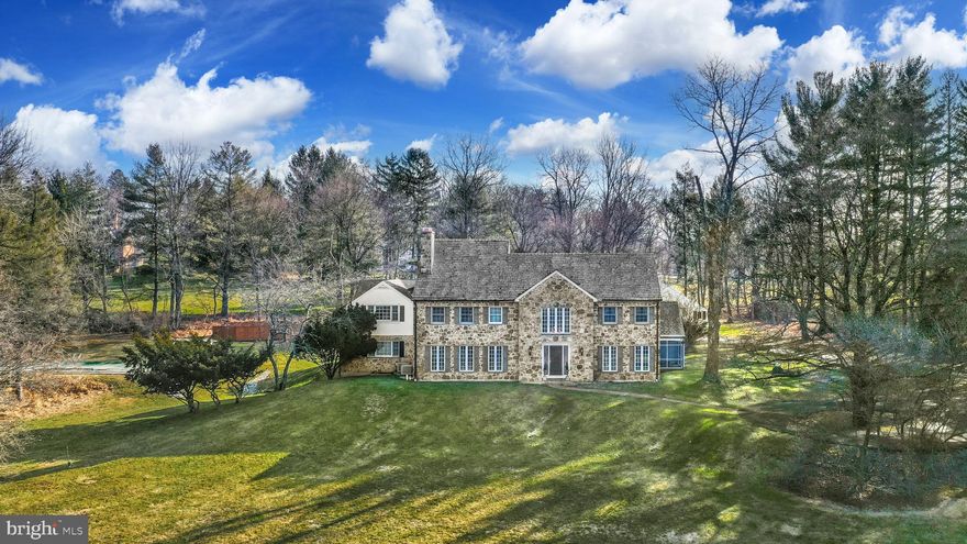 Set in the stunning environs of Saucon Valley, this classic stone home was designed to take advantage of its hillside location atop 3.7 acres. Built in 1955, it was updated in 1995 with a fabulous makeover. Boasting over 6,600 square feet of family space on three levels, this sophisticated home has been beautifully executed. At entrance, the marble-floored, two-story foyer presents a custom, curved staircase. Hardwood floors accent most first floor rooms. The kitchen features appliances such as Viking, Miele and Thermador, and custom cabinetry. A butler’s pantry and an adjacent, sun-filled breakfast room are guaranteed to impress. A gracious dining room and living room have detailed moldings and a fireplace. A central family room is anchored by a second fireplace with Mercer tile and opens, through mullioned glass pocket doors, to a library. Completing the first floor is an ensuite bedroom, half bath and 2nd staircase. Upstairs, there are 4 additional bedrooms, a fireplace, four baths, laundry and a vaulted sitting area. The lower level offers a recreation room with fireplace and wet bar, and plenty of storage and workshop space.  Outside, shaded by splendid trees, there is an inground pool with sunset vistas and a detached, three car garage with plumbing and walk-up second floor.   A patio, screened porch, 22K whole house generator and attached two car garage are the finishing touches to this exceptional home.