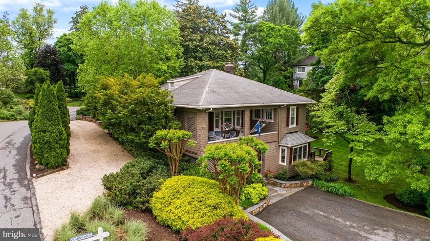 1409 Locust Avenue, nestled in a prime Ruxton setting, perfectly marries historical charm with contemporary updates. This exquisite property, originally built around 1904, has been meticulously updated and expanded to cater to contemporary lifestyles while retaining its timeless charm. It boasts four bedrooms, three and a half baths, and is situated on approximately half an acre of professionally landscaped grounds, offering a serene park-like setting. The home’s layout promotes an exceptional flow, seamlessly integrating indoor and outdoor living spaces with multiple decks and a covered porch, particularly off the primary bedroom, to enhance the enjoyment of sunsets and idyllic surroundings. The interior of the home welcomes visitors with a two-story foyer, featuring an elegant paneled entry door with sidelights, and full-height transoms that invite natural light to sweep across the beautiful hardwood floors with inlaid borders. The entrance flows directly into the living room, accented by a two-story beamed ceiling and a warm pine flooring. A wood-burning fireplace with a traditional mantel and marble surround creates a cozy ambiance. The living room offers two sets of French doors that lead out to a spacious deck, allowing guests to effortlessly transition between the warm interior and the lush outdoor environment. The primary suite on the upper level includes a brick wood-burning fireplace and hardwood flooring and opens onto a private covered porch, providing exclusive views of the gardens. This suite further includes a stylishly appointed and recently updated primary bath with a glass-enclosed subway-tiled shower and elegant marble flooring. Additional bedrooms include amenities such as custom cedar closets and private access to baths. 1409 Locust Avenue is a wonderful Ruxton gem, where historical architecture meets modern convenience in a prime location. This property offers a beautiful backdrop for daily life, enjoying classic features enhanced by thoughtful contemporary updates, making it an ideal sanctuary!