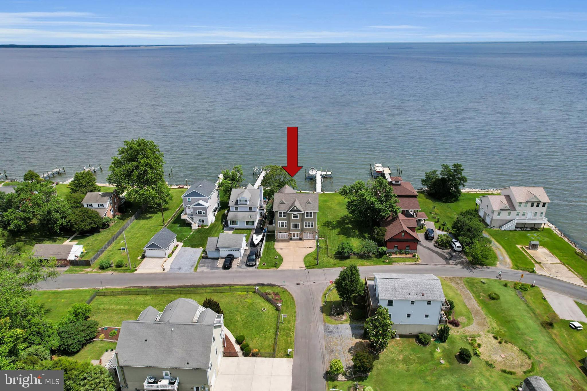 Discover this stunning custom-built home on the Chesapeake Bay, showcasing breathtaking waterfront views. Nestled on nearly half an acre with 100 feet of shoreline, this retreat features a maintenance-free composite pier with over six feet of water depth, a 10,000 lb boat lift, and a jet ski lift. Unwind in the hot tub on the deck while watching the ships pass by, or enjoy magnificent sunrise views from the screened-in porch. As you take in the waterfront scenery, you might spot osprey, hawks, ducks, eagles, otters, and occasionally even dolphins and stingrays. The interior of the home is equally impressive. The main level welcomes you with a sun-filled entryway and two oversized garage spaces, both of which open to the waterside yard—perfect for summertime entertaining. The second level boasts a gourmet kitchen with custom cabinetry, granite countertops, and stainless steel appliances. Charming cathedral and exposed beam ceilings enhance the living space. The open floor plan incorporates a dining area that seamlessly connects to the family room, where a wall of windows showcases stunning views. A gas fireplace and custom-built cherry cabinets add warmth and elegance. This level also includes gleaming hardwood flooring throughout, along with two bedrooms—one featuring an ensuite bath—and a conveniently located powder room. The third level is dedicated to the primary suite, offering beautiful views, an ensuite bathroom, access to the screened-in porch, and a laundry center for added convenience. On the top level, you'll find an incredible space that can serve as a fourth bedroom, office, or media room. This area features wood floors, a wet bar, an electric fireplace, and an abundance of storage space. Additional features of this home include a generator backup system, a built-in home stereo system, a covered patio, an irrigation system, and space provisions for a future elevator. The desirable Bayside Beach community features a beautiful sandy beach, two boat ramps, a playground, and a covered pavilion equipped with seating and electric service. It is conveniently located near marinas, Compass Pointe Golf Course, and the 90+ acre waterfront Fort Smallwood Park, as well as nearby restaurants. This home offers an ideal setting for waterfront living. Make it yours to enjoy this summer!