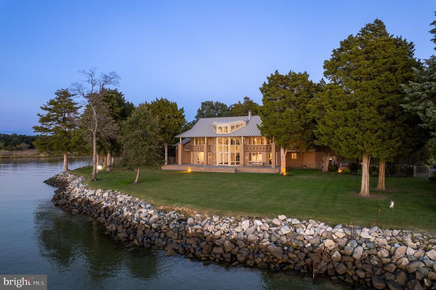 Tucked within a canopy of trees along Maryland’s Eastern Shore, this remarkable home rests quietly beside the Choptank River. The setting feels worlds away, eighty acres of meadows and woodland that open gently to more than 1,800 feet of private shoreline, where a western exposure captures breathtaking sunsets reflected across the water.

The residence at 5084 Ferry Neck Road was shaped by owners whose careers in fine contemporary art inspired a deeply thoughtful approach to design, one that explored geometry, light, and proportion with an almost abstract eye. The resulting octagonal plan draws the landscape into every room, creating a calm rhythm of space and view.

A low, horizontal brick façade settles the home into its surroundings, while a lifted roofline and generous overhangs give shelter and balance. Inside, a sweeping staircase curves upward through the central volume, a graceful gesture that anchors the home with quiet strength.

In 2024, the property underwent a comprehensive renewal. Porcelain countertops, new glazing, and refined lighting bring a fresh modern sensibility while honoring the original architecture.

Approached by a long, tree-lined drive, the home reveals itself gradually, first a glimmer through the woods, then an opening to water and sky. Beyond its immediate beauty, the land itself offers a rare opportunity, with the potential to create a divisible waterfront homesite should the next owner wish to explore it.


What remains most striking, however, is its sense of comfort, a home that is inviting, shaped by art, nature, and time.