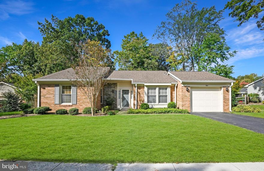 Rare offering  on .34 acres with verdant gardens extending to wooded privacy / This hard-to-find peaceful setting is most enjoyed from the flagstone patio and large screened porch addition with vaulted ceiling and skylights, constructed with low-maintenance synthetic materials / Well-designed floor plan with spacious bedrooms plus den reveals ample closet and storage space throughout / Harris hardwood floors modernize the social spaces and bedrooms / Living room showcases a gas fireplace between picture windows overlooking the wooded perimeter / Remodeled kitchen is outfitted with cherry cabinetry, granite counters and upgraded stainless steel appliances inc. a 5-burner smooth surface range with suspended range hood / Remodeled primary bath features a double granite vanity and custom tilework / 2nd bath with tile floors and bathtub-shower surround has had minimal use and looks new / Oversize garage incorporates  a wall-to-wall workbench, useful storage shelving, pull-down stairs to additional floored attic storage while still accommodating your car! / No propane tank needed with the natural gas furnace (high-efficiency Trane HVAC in 2014), fireplace and outdoor grill connection / This popular 55+ community offers indoor and outdoor pool, tennis, golf membership, kayaking, walking-jogging paths, billiards, bocce, library and much more.