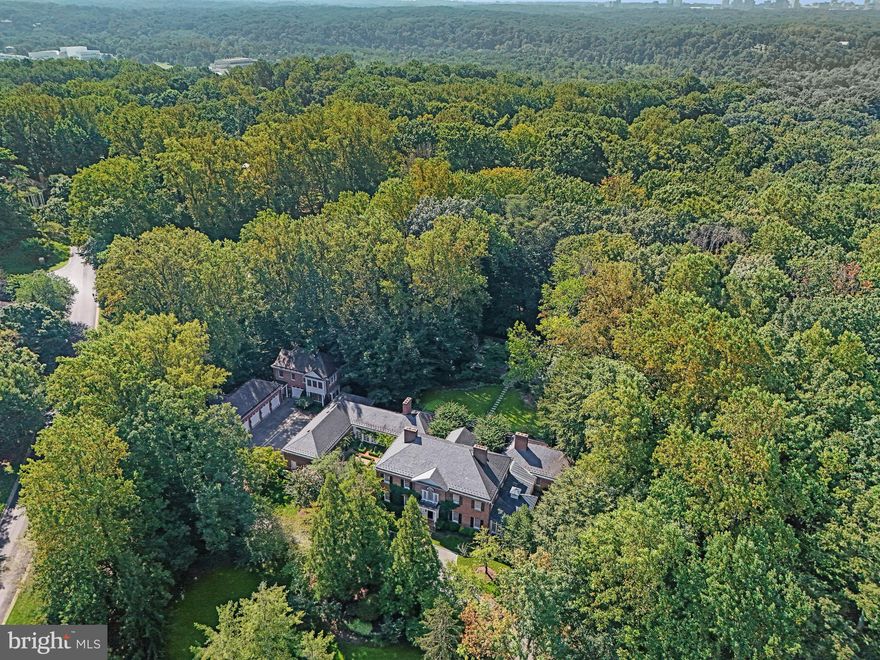 Nestled on 2.56 acres in the coveted Eagle Ridge section of award-winning Avenel, this Potomac estate was originally designed by the renowned Natelli Homes for a prominent hotelier family who had a love of architecture, gardens, and car collecting. A graceful approach reveals the Georgian façade, evoking a sense of timeless sophistication through its symmetrical design, ivy-covered walls, and classic slate roof.
Entering the grand center hall transports you to an era of old-world elegance. A bygone level of craftsmanship is evident throughout the 12,000-square-foot expanse. The arched Palladian window above is surrounded by intricate millwork — found throughout the home — and bathes the inlaid marble floors in natural sunlight.Embassy-sized formal living and dining rooms flank the reception hall, each with its intricate fireplace — two of seven in the home. The living room serves as a gateway to the conservatory with three walls of windows and soaring ceilings. A mahogany-paneled office/library with a roaring marble fireplace sits adjacent. The marble transverse gallery bisects the entire width of the main level and accesses the rear lawn via multiple sets of French doors. It connects formal and informal areas, which revolve around a modern and open kitchen. Its light cabinets and Carrara marble countertops contrast beautifully with the tile flooring. Within the kitchen is a breathtaking breakfast nook with a curved bay window that offers tranquil views of the English courtyard. The grand family room has a soaring honed limestone fireplace flanked by illuminated built-ins and herringbone floors. More French doors open to the rear lawn, affording true indoor/outdoor living.
Opening directly onto the garden is the main-level primary suite. While the windows create a natural oasis, its location at the rear of the home provides both tranquility and privacy. The suite is complemented by a spacious, sumptuous bath clad in marble, several walk-in closets, and a fireplace. At the main stair landing is an upper-level gallery with cathedral ceilings and garden views. Four ample-sized bedrooms occupy respective corners of this level and are served by equally accommodating ensuite baths.
On the walkout lower level, the open recreation room is paneled and boasts an intricately coffered ceiling while overlooking the second courtyard and pond. The stone floors are arranged in a striking Versailles pattern. The division into multiple areas centered around an inviting 2-sided fireplace creates distinct yet connected spaces. Bonus rooms offer ideal flexibility for the likes of a home gym or yoga studio.
Outside, an artful combination of hardscaping and landscaping creates a private, wooded paradise. The sunken side patio is permeated only by the sounds of flowing water from the custom waterfall and pond. The hardscaping has been crafted to mirror the estate's overall symmetry. Outside the main gallery is a cozy seating area stepping up to a grassy lawn leading to a 40-foot heated swimming pool with an automatic cover. The pool is surrounded by flagstone and features a picturesque fountain. It's tucked away at the rear of the property with abundant trees that provide a natural canopy. An outdoor fireplace and BBQ area with a gas hookup are adjacent. The estate's pièce de résistance are the facilities catering to the automobile enthusiast. 13 garage bays were built around the motor court, affording enclosed storage space for one's collectible vehicles, art collections, or a golf simulator. A climate-controlled workshop and a separate guest house above the garage bays—self-sufficient with a full kitchen, living area, two bedrooms, and a full bath—complete the offering. Eagle Ridge is the southernmost village of the Avenel golf community. It is the most accessible to DC and Northern Virginia. 9900 New London embodies the very ethos of Potomac while offering unparalleled proximity to Washington.