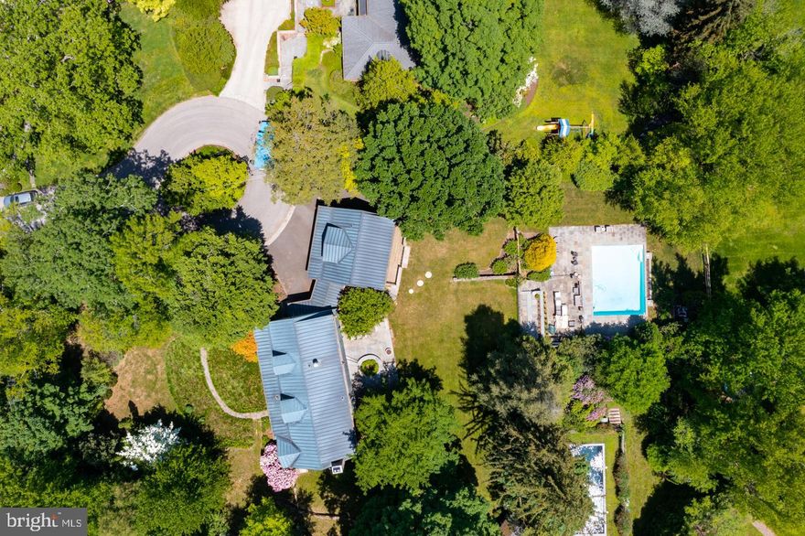 Moments beyond the vibrancy of Chestnut Hill, an oasis awaits on a cul-de-sac in Wyndmoor. From the outside, this elegant mid-century Cape Cod with copper gutters and lush landscaping charms immediately. Once inside, the full story of this property unravels. It's your own private sanctuary, where the back of the house is lined with windows revealing a sprawling backyard complete with swimming pool and old growths . Pull into the driveway, then enter through the side door. A stone mudroom lined with custom cabinetry and a deep coat closet is there for you to drop off the day's gear. A set of French doors lead into the main floor - open throughout, but segmented enough for each room to have its own personality. Stunning wide-plank white oak Carlisle flooring throughout this level and most of the second makes walking barefoot joyful. You'll find two vast living spaces that flank a beautiful kitchen. Renovated in 2017, it has marble countertops, a farmhouse sink, 6-burner Viking stove, GE monogram refrigerator, and Bosch dishwasher. Its proximity to the dining alcove makes it the perfect place to host a convivial dinner party. Each living space has built-in shelving, its own fireplace (one wood-burning, one decorative), and access to the expansive outdoor patio overlooking the pool and surrounding woods. As you head upstairs, you'll pass one of four bedrooms in the house and the first of three full bathrooms. On the second floor, the bedroom to the right has a full wall of California Closets and a newly renovated ensuite bathroom. Two more generous bedrooms exist on this floor - each offering the same tranquil view shared by the main floor's rooms. Take the possibilities a step further to create a main bedroom suite, which would include one of these bedrooms, another newly renovated bathroom and bonus area to be used how you see fit. Throughout the house, there is an abundance of storage space - especially upstairs in deep bonus closets and outside of the house in the spacious two-car garage. Above this garage is a private suite with a vaulted ceiling offering a sense of grandeur. With a full bathroom, full-sized refrigerator, and doors that open onto a private deck overlooking the grounds, it's perfect for out-of-town guests, a gym, or perhaps even an after-swimming gathering place!