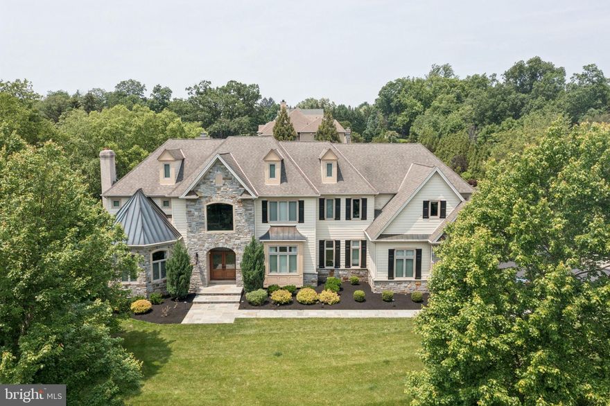 Welcome to 801 S Penn Oak Rd, an extraordinary estate that blends architectural elegance with modern comfort. The impressive two-story foyer sets the tone, opening to bright, flowing spaces perfect for gathering, working, and relaxing. The inviting family room sits just off the entrance, while the dramatic two-story living room features a cozy fireplace, soaring ceilings, and walls of windows overlooking the pristine backyard.

At the heart of the home is the stunning contemporary chef’s kitchen, outfitted with top-tier appliances—professional-grade range, double ovens, and an oversized refrigerator. Sleek quartz/stone counters, a large center island, custom cabinetry, under-cabinet lighting, and a walk-in pantry create the ideal space for everyday living and elevated entertaining.

The main level also offers a formal dining room, dedicated office, and a rare first-floor bedroom that could be converted into an office, with a private full bathroom—perfect for guests or multigenerational living. A powder room completes the floor.

Upstairs, four spacious bedrooms include the exceptional primary suite with a seating area, two walk-in closets, and a spa-inspired bath with dual vanities, soaking tub, and a large glass shower. Each additional bedroom has its own full bathroom. A finished attic provides a flexible bonus space ideal for a studio, playroom, or extra living area.

The fully finished basement transforms the home into an entertainment destination, featuring a star-lit movie theater, gym, chic bar and lounge, and a full bathroom.

Outside, a resort-style oasis awaits: a heated, fenced-in in-ground pool with integrated spa, expansive bluestone patios, and a large covered pavilion with wood ceiling, heaters, speakers, fan, and TV hookup. The fully equipped outdoor kitchen—with built-in grill, burners, sink, refrigerator, and storage—sets the stage for unforgettable gatherings.

Beautiful landscaping, stone walls, mature trees, garden area, children’s playset, and multiple seating areas enhance the private grounds. A spacious three-car garage completes this remarkable property.