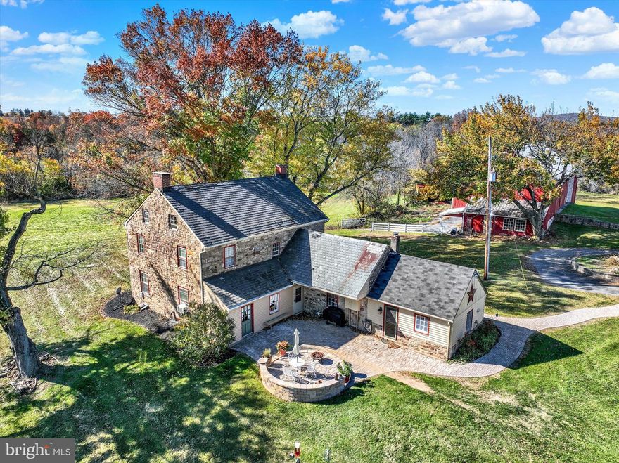Prepare to fall in love...Tucked down a long driveway and flanked by open space, settle into this 4 bedroom 1816 stone home.  The kitchen has exposed barn beams and a copper hood over the original bake oven.  The dining room has an open hearth fireplace and still exhibits some of the original wall stenciling.    The living room and sitting room both have working fireplaces, gorgeous built-ins and deep windowsills.  There are hardwood floors throughout most of the main floor and in the upstairs 4 bedrooms.  The bank barn has 2 horse stalls with room for more.  Not completely enclosed but a large area that served as the pasture is outlined in page wire fencing.  The front barn is mostly storage.  The detached 4-car garage with 2-18' garage doors and 1/2 bath doubles as a nice pool house next to the 8' inground pool.
