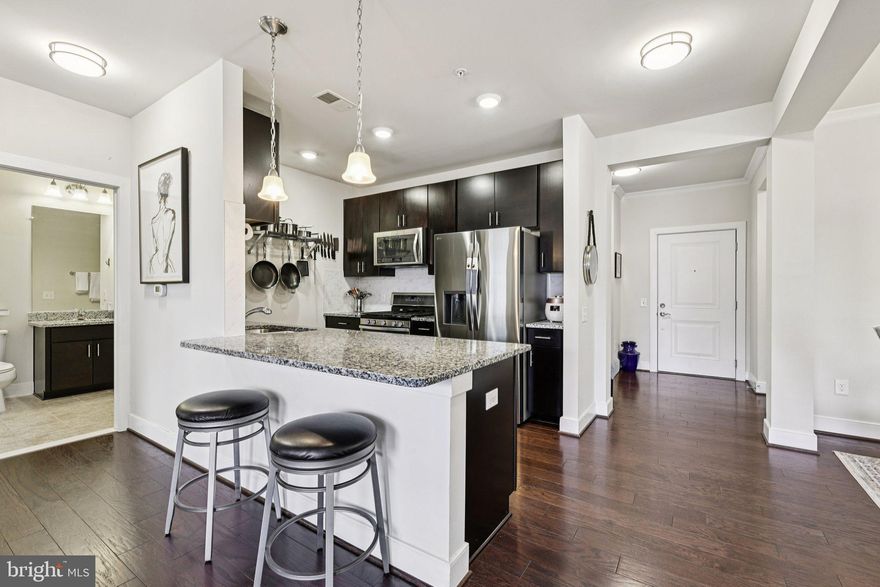 Welcome to refined, low-maintenance living at The Flats at MetroWest—a beautifully maintained second-floor condo unit offering 1,506 sq ft of light-filled space, modern upgrades, and exceptional convenience just steps from the Washington Metro Orange Line at the Vienna/Fairfax–GMU Metro Station. This owner-occupied residence showcases an expansive open-concept layout designed for comfortable everyday living and effortless entertaining. Soaring ceilings and oversized windows fill the home with natural light, while the spacious living and dining areas flow seamlessly to one of the largest balconies in the community. The gourmet kitchen is both stylish and functional, featuring granite countertops, stainless steel appliances, upgraded maple espresso cabinetry, a tile backsplash, abundant storage, and a generous peninsula with breakfast bar seating—ideal for casual dining or hosting guests. The oversized primary suite serves as a true retreat with a spa-inspired en-suite bath complete with dual vanities, a luxurious soaking tub, walk-in shower, upgraded fixtures, and a large walk-in closet. A spacious bonus office/den provides flexibility for working from home, guests, or additional living space. Additional highlights include:
• Over $42,000 in builder upgrades
• Upgraded hardwood flooring, carpet, and padding
• Two deeded tandem parking spaces (#45 & #46) in a secure underground garage
• Low $396/month condo fee including water and trash
• Exceptionally low utility costs and regular biannual HVAC maintenance. 
Residents enjoy access to the nearby Jim Scott Community Center with complimentary fitness facilities and classes, while the location places you minutes from premier shopping, dining, and entertainment in Fairfax City, Vienna, Mosaic District, and Tysons Corner. Commuters will appreciate easy access to Interstate 66 and Interstate 495 for seamless travel throughout Northern Virginia and Washington, DC.
Offering space, thoughtful design, quiet surroundings, and unmatched accessibility, this exceptional condo is ideal for professionals, couples, or anyone seeking luxury, convenience, and value in one of Northern Virginia’s most desirable communities.  Easy to show, don’t miss this one!!!