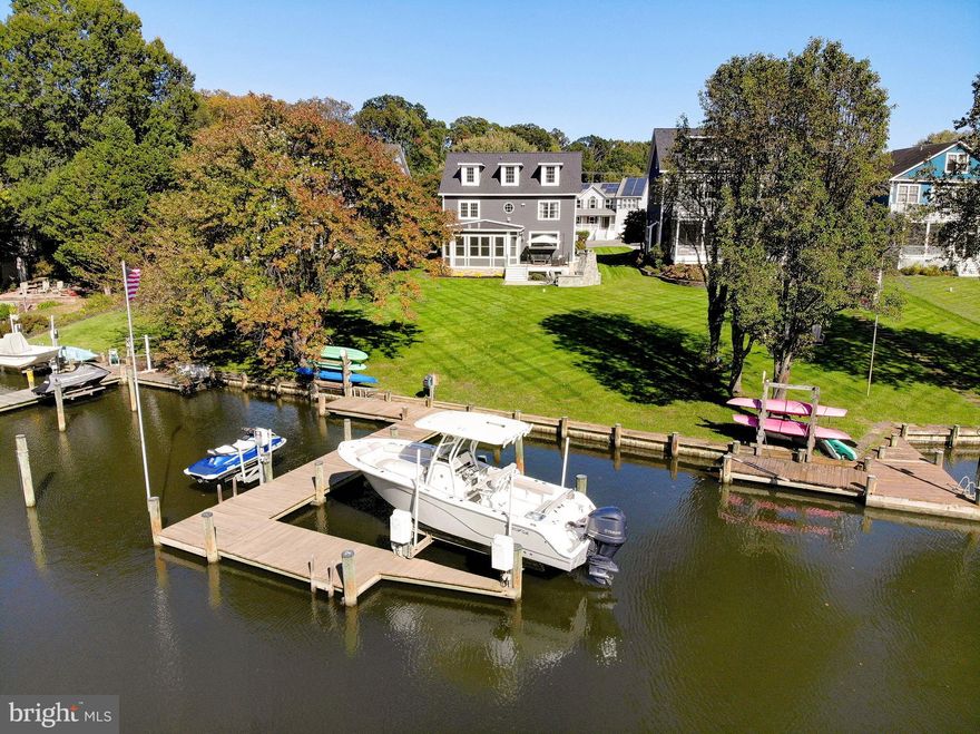 Experience refined waterfront living in this completely reimagined home located in the coveted Loch Haven community, perfectly positioned on the protected waters of Pocahontas Creek with approximately 4 feet of mean low water and just seconds from the South River. This exceptional property offers the ideal blend of serene privacy, premier boating access, and sophisticated design. The home has been meticulously renovated from top to bottom and showcases an expansive open-concept layout designed to maximize both water views and natural light. In addition to the stunning cosmetic transformation, the home features major recent improvements including a brand-new roof, two new HVAC systems, and a newer water heater, offering true peace of mind. At the heart of the home is a stunning gourmet kitchen featuring a large statement island, Thermador stainless steel appliances, quartz countertops, custom tile backsplash, and a picture window perfectly framing the waterfront scenery. The kitchen flows seamlessly into the family room, highlighted by a  linear fireplace with shiplap surround and custom mantel, and continues into the sun-drenched dining area wrapped in walls of windows. The main level also offers a thoughtfully designed mudroom with built-in lockers, a laundry room, a stylish powder room, and a generously sized private office. Throughout the home, you’ll find luxury wide-plank flooring, reinforcing the home’s cohesive, high-end aesthetic. The primary suite is a true waterfront retreat, offering water views, a sitting area, a private fireplace, and a spa-inspired bath with a freestanding soaking tub, oversized walk-in shower, and double vanity. Two additional spacious bedrooms and a beautifully updated full bath complete the second level.
The third floor provides incredible flexibility with a fourth bedroom featuring water views, an additional flex space or fifth bedroom/office, and a newly remodeled full bath—ideal for guests or multi-generational living.
The lower level offers a recreation room, gym, full bathroom, ample storage, and utility space—perfect for both everyday living and entertaining. Outdoor living is nothing short of spectacular. The dining area opens to a deck with glass railings that flows down to a waterside patio with a dramatic stone fireplace, creating a resort-like setting for entertaining or relaxing by the water. The professionally maintained grounds are supported by the irrigation system, and the private pier features a 10,000 lb boat lift and kayak storage, making this a true boater’s dream. With a flat, usable waterfront lot, protected deep water, and luxurious upgrades throughout, this is a rare opportunity to own a turn-key waterfront home in one of the area’s most desirable communities.