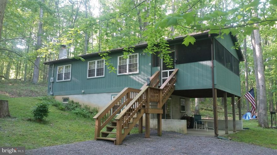 Like New! Cabin in the woods with Cacapon River Access. Unique design ads to the appeal with a separate master suite potential, open floor plan with woodstove, stone hearth, cathedral ceilings, laundry room. and enough sleeping for 8 comfortably, 2 full baths. Large screen porch for enjoying the evenings after a peaceful day on the nearby river. 5 Wooded acres. Wild Wonderful WV Awaits!