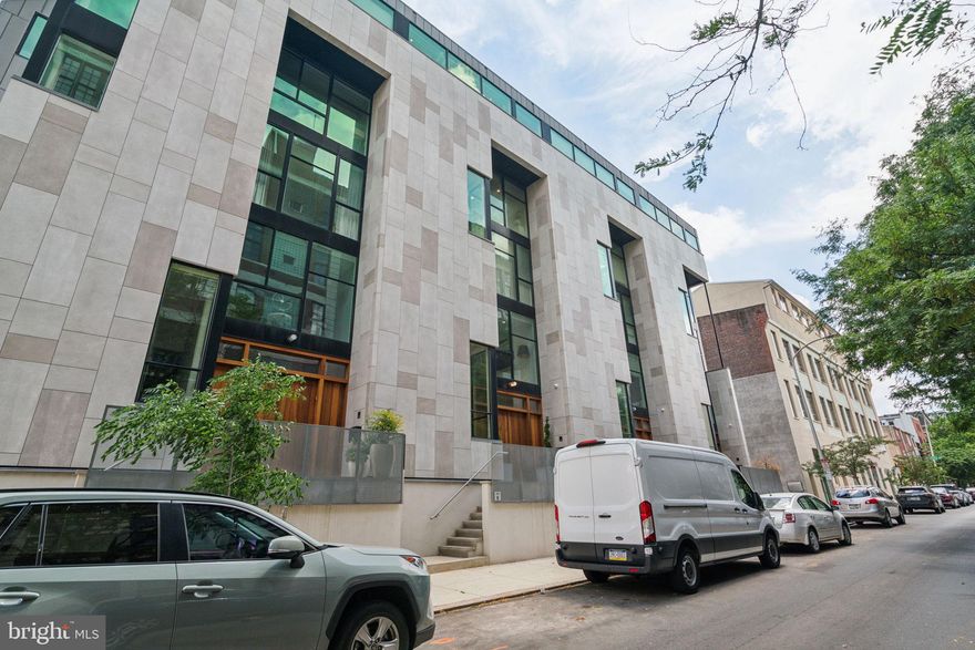 No detail was missed in the design and build of this spectacular five-story home! Located in the prestigious Fitler Nine community, this modern residence includes 4 bedrooms, 4 full bathrooms and 2 half bathrooms, multiple living and entertaining spaces, private roof deck with Center City skyline views, finished lower level, underground 2-car garage parking bay, elevator, incredible natural light, and white oak hardwood floors throughout. Enter through a massive oak front door into the grand great room with a living and dining space and open chef’s kitchen. The living area features a gas fireplace with porcelain surround and built-in closets with a EuroCave wine fridge. The dining room is a spectacular double height space with a wall of floor-to-ceiling windows. The open chef’s kitchen offers flat panel wood cabinetry, porcelain countertops and backsplash, a large waterfall island with breakfast bar, deep sink with a bonus filtered faucet offering instant hot and cold water, pot filler, walk-in pantry, and a high-end Thermador appliance package. Off of the kitchen is access to the secure community courtyard with beautiful landscaping and sunlight. There is a conveniently located hidden pantry and powder room behind the kitchen. The next three levels of the home feature 4 bedroom suites each with their own ensuite bathrooms with TOTO toilets and marble-appointed showers. The second floor has a spacious open family room with built-in entertainment console that overlooks the first floor by way of a half glass wall. Adjacent is a bedroom with an ensuite bathroom that is also accessible from the family room. The entire third floor is a lavish primary suite that enjoys excellent natural light from oversized windows, a large dressing area with multiple built-in closets, and a glass door leading to a large French balcony overlooking the courtyard. The ensuite primary bathroom offers a wall of floor-to-ceiling windows overlooking 24th Street, porcelain tiled floor and walls, radiant heated floors, double vanity with built-in storage, large air jet tub with temperature-controlled faucet that fills from the ceiling, and a huge walk-in glass enclosed shower. The fourth floor has a second family room with double height ceiling, a laundry room with side by side Whirlpool washer and dryer, and two generously sized bedrooms with ensuite bathrooms. The fifth floor Pilot House has a glass balcony overlooking the family room below, kitchenette with mini fridge/freezer and Thermador dishwasher, a powder room, and access to the roof deck—the place to be on a beautiful day! In addition to magnificent skyline views, it offers a built-in Coyote grill and Il Fornino wood-burning pizza oven, hose hookup, and space for outdoor dining and entertaining. The finished lower level has a huge walk-in closet with built-ins, a second walk-in closet, and access to the underground two-car garage parking space with Tesla charging station. The garage is shared, but each residence has their own dedicated parking bay. Additional home highlights include a Control4 smart home system, two-zone HVAC and mini split on 5th floor, Porcelanosa brand tiles, custom handmade built-ins, recessed lighting throughout, and a tax abatement. It is located only one block from the Schuylkill River trail and park which offers a playground, dog run, sports fields, and community garden. World-class dining and retail as well as Rittenhouse Square are all within walking distance. Short commute to CHOP, Penn, Drexel, and 30th Street station.