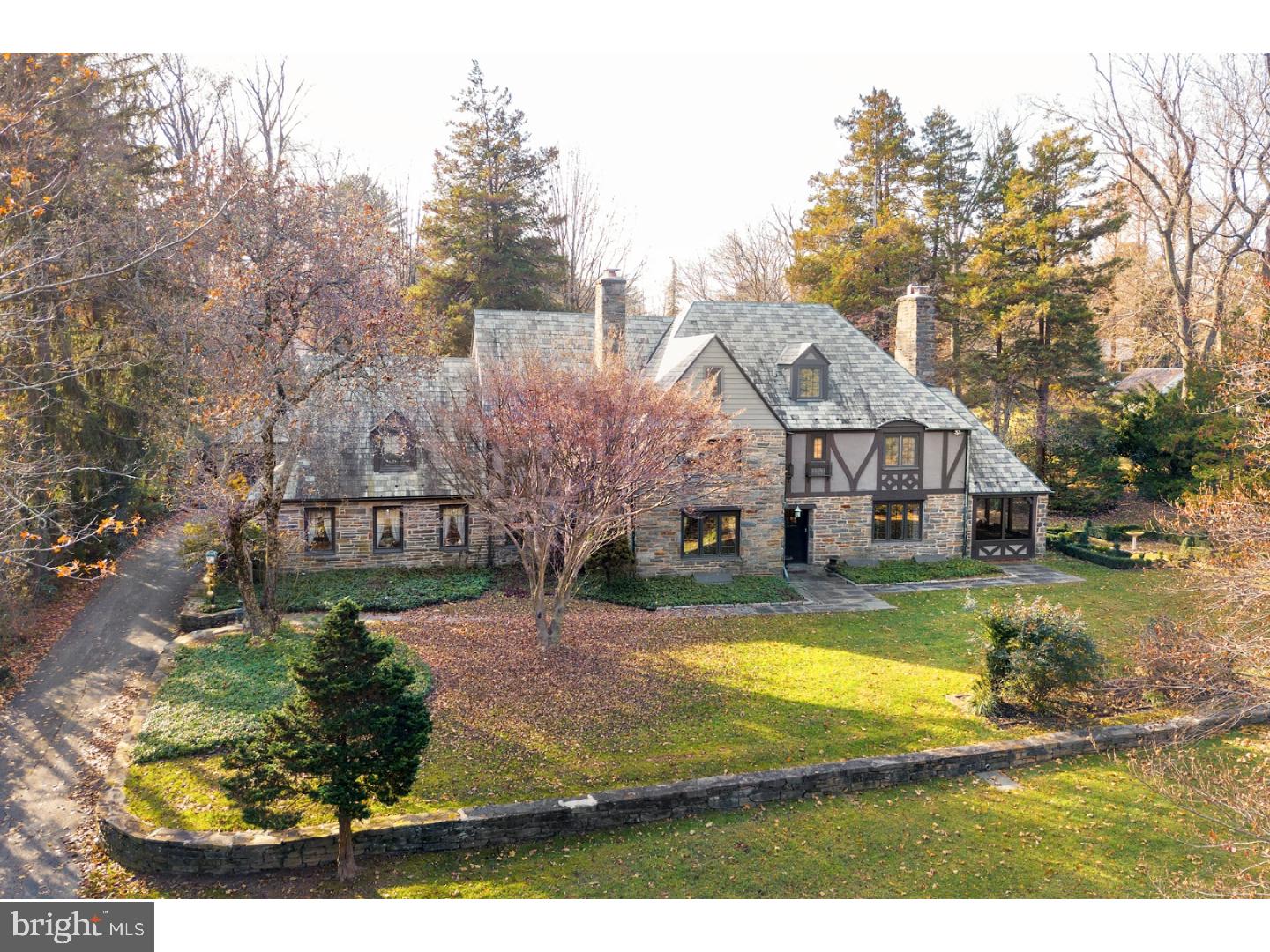 Beautiful 5-6 Bedroom stone Tudor set on a magnificent 1.82 acre lot of flat yard space near prominent Merion Golf Club. Enter this home to a reception hall with powder room, handsome office with built in shelving and hand embossed leather wall panels, and stair to the second level. To the right of the reception hall find an elegant and bright Living Room with fireplace and French Door entry to a relaxing three season room. To the left of the hall, find a charming dining room with entry to the home's kitchen. Tastefully renovated, the kitchen offers an oversized soapstone topped center island with sink, seating, and storage beneath, wet bar with wine chiller, a mixed quartz mosaic backsplash, high grade appliances such as a Wolf six burner range with griddle and built in subzero refrigerator and freezer. Seamless entry room the kitchen into the open family room with large, built in shelving and entertainment center. This open space is accented by exposed wooden beams and brightened by plenty of surrounding windows. Ascend the stair to the second level and to the left enter the spacious and luxurious Master Suite with walk-in closet space and separate His and Her bathrooms. Three family bedrooms, two baths, and laundry complete this level. A finished third level offers additional family or guest space with sitting area, two rooms, one of which is currently used as an office, and a full bath. Finished and spacious lower level with fireplace and wet bar provides plenty of recreation or entertaining space. A flagstone terrace offers stunning and breathtaking views of the mature landscaping surrounding the property. Truly one of a kind home and a must see for any discerning buyer.
