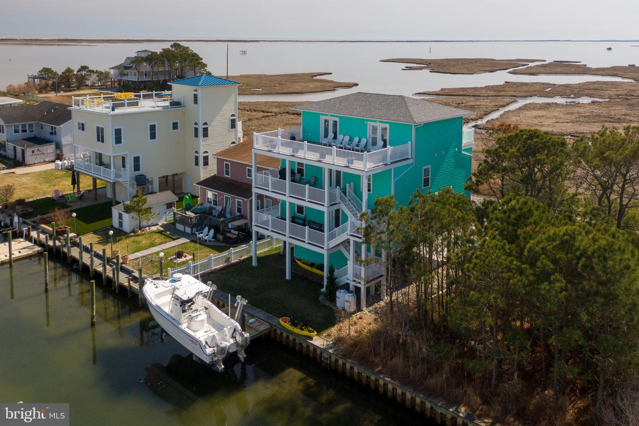 Be careful this home will steal your heart! Minutes from Ocean City or Assateague Island beaches, Frontier Town, water park and the shops in old town Berlin. There are three golf courses and a driving range within two miles and several others close by. Or stay at home and enjoy the canal that flows to the Bay. The list of activities are endless and right at your own private bulkhead. Go boating, fishing, clamming, crabbing, paddle-boarding or on a relaxing kayak ride. There are so many experiences to enjoy. But be sure to be back for the stunning sunset with a cocktail in hand to watch from one of the six decks. There are breathtaking views of Assateague Island National Park, The Verrazano Bridge, Sinepuxent Bay and the Atlantic Ocean. Wetlands in front assure a view forever as they are protected by the state.
You can watch the horses graze along the beaches and listen to the ocean waves crashing off in the distance. With a brand new 15,000# Neptune elevator boatlift, you have close access to the bay or minutes from World renowned fishing. Two carports with plenty of space for off street parking. This fully furnished home was built in 2019. The ground floor has a welcoming foyer with a large utility room with a freezer and loads of storage space.
This house has fabulous rental income potential…ready to go – just add guests!
The second level has a coffee bar area, laundry room and four bedrooms, each with their own full bath. Custom tiled showers (and one with a tub) with showerhead/handheld functions and comfort height toilets in each. You can enjoy coffee on your front or rear porches while watching nature wake up each morning. The rear porch has a wall mount fan for hot days of reading by the canal.
The third level has a spacious open floor plan with a large living room and offering a gas fireplace for those cold nights, that flows into the huge kitchen for the cook in the family. Spacious enough for more than one cook! Large deep main kitchen sink and island prep sink. There is a full-size separate freezer, and refrigerator, built-in microwave, double wall ovens and propane 5 burner cooktop with downdraft exhaust. Beautiful KraftMaid wood cabinets with loads of storage space. Bar countertop seating for 8.
This level also boasts an Owners Suite with a full-size washer & dryer and the bathroom has separate thermostatic controls so you and your spouse never have to adjust the temperature…one likes it hot and the other cold? NO problem!
Work from home? There is a full size office with plenty of drawers, lateral filing cabinet and lovely granite top. The gorgeous view makes it almost impossible to be stressed. Just outside of the office is a Powder Room for your guests.
The third level rear deck has a propane gas connection with a Nexgrill stainless steel 5 burner grill.
The fourth floor is a rare find! It is huge and ready for entertaining. A large counter with a bar sink, wine rack and solid wood cabinets has amazing storage space . There is a stainless steel french door refrigerator for your beer and cocktails and an 84” TV for movie night or karaoke fun! The other half of the fourth floor has an 8 foot pool table just waiting for you pool sharks! There is a Powder Room with a porthole window that overlooks the ocean. The rear deck is enormous and just waiting for you to add your finishing touches. It overlooks the canal, bay and Assateague and has an electrical outlet for a retractable sunshade if you so desire. Such a large space for lounging, entertaining or watching the planes fly over during the air show or fireworks during July. The front deck offers the breathtaking views of Assateague National/State Park and is perfect for spending time with friends and family watching the boats, water activities and native birds. THIS HOME IS READY FOR YOU... AND WAS DESIGNED AND CREATED FOR ENTERTAINING, ENJOYING & EXPERINCING THE BEACH LIFE.