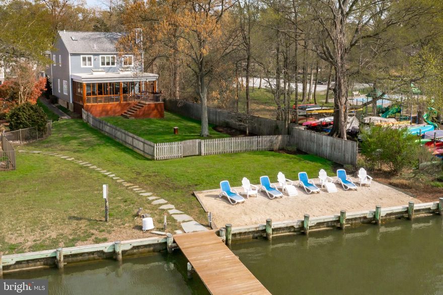Bay Ridge Waterfront with protected deep water boat slip and shared dock on Lake Ogleton.  Lot has rare, private sandy beach and expansive sunsets! Boasting over 3700 sq. ft., this open floor plan home takes full advantage of the water views with the oversized three-season porch. Offering generous sized rooms, high ceilings, tons of windows and an abundance of natural light.  The gourmet kitchen features an oversized refrigerator, 5-burner gas stove, stainless steel appliances and island.  Gas fireplaces in living and family rooms. Custom bar in dining room with bar stools and sink is perfect for casual entertaining. Amazing water views from the primary upper level bedroom, vaulted ceilings, ample walk-in closet space, and large bathroom.  Detached two-car garage with additional storage and there is ample parking in driveway.