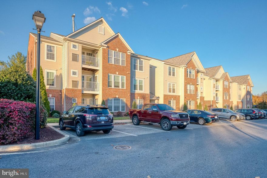 Experience sophisticated condo living in the heart of Perry Hall Farms with this 3rd-floor unit offering 2 beds and 2 baths. The foyer welcomes you with gleaming hardwood floors, leading to a freshly painted interior complemented by brand new carpeting throughout. A spacious living/dining combo features a double-sided fireplace, high vaulted ceilings, and access to a charming balcony. The kitchen, adorned with stainless steel appliances and a stylish backsplash, overlooks the living/dining area and boasts a breakfast bar and hardwood flooring. French doors reveal the convenience of an in-unit laundry room. The primary suite presents an attached bath and a generous walk-in closet, while an additional bedroom features its own attached bath. This unit includes an assigned parking space for added convenience and the furnace is just three years old! Nestled in the vibrant Perry Hall community, this home is within reach of local shopping and dining, offering a comfortable and stylish living experience.