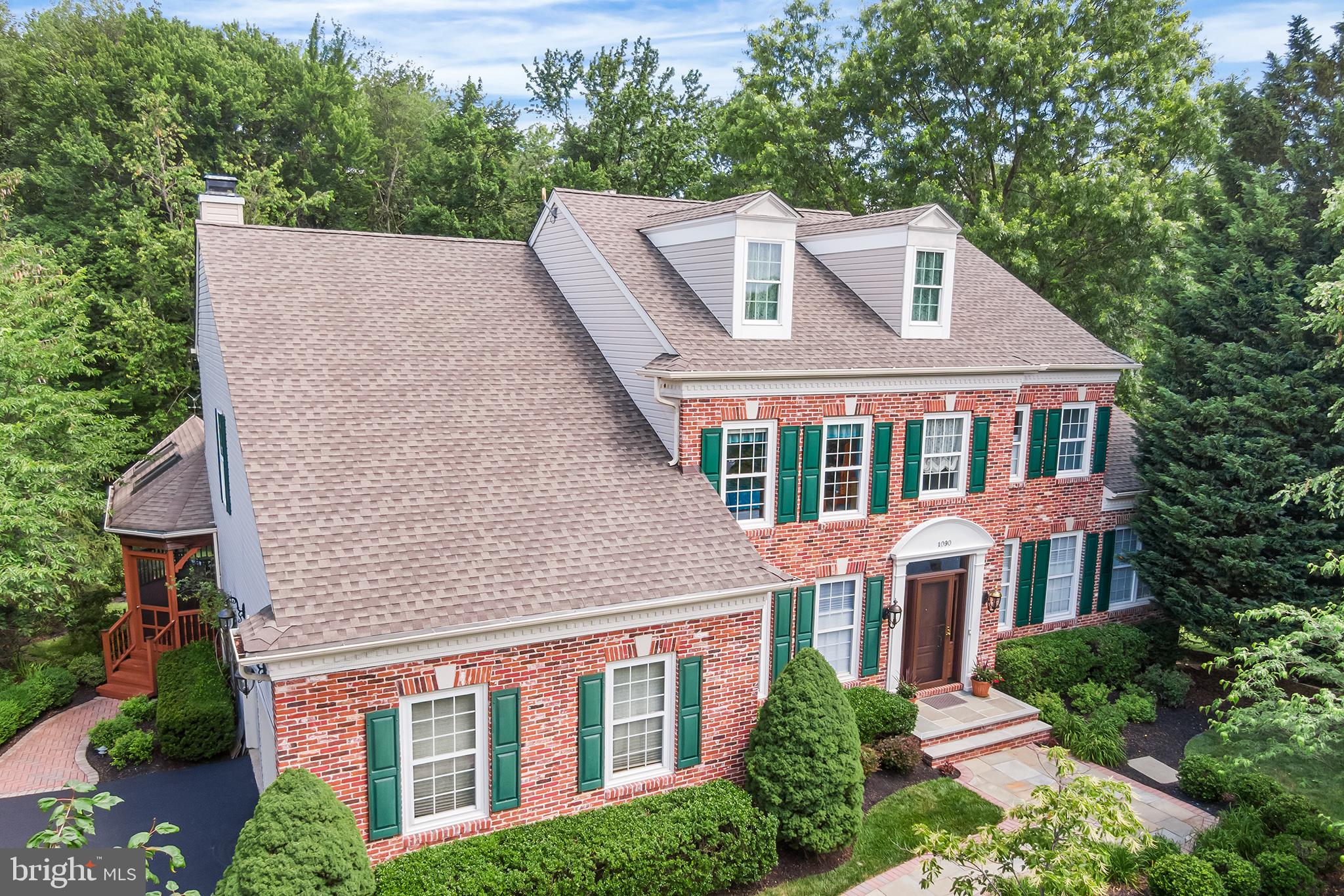 Welcome to 1090 Bancroft Ln, a beautiful brick colonial in desirable Wyndham of Yardley. Situated on a quiet cul-de-sac, this premium lot backs to a wooded 5.3-acre conservation easement offering gorgeous views and ample privacy. Upon arrival, you will appreciate the extensive hardscaping and landscaping with landscape lights and in-ground irrigation system. Follow the bluestone walkway to the front porch with new front door and sidelights. The bright and airy 2-story foyer with turned staircase and hardwood floors is the perfect place to welcome guests. To the left is the study, an ideal home office. To the right is the expanded formal living room with gas fireplace and crown molding. The living room flows right into the expanded formal dining room with crown molding, creating a wonderful space for entertaining. The kitchen features oak cabinets, Corian counters, and stainless-steel appliances including a Bosch Dishwasher and Fivestar Dual Fuel Gourmet Range with 6 burners, grill/griddle, double oven, and professional hood with warming lamps. A 7’9” center island is the heart of the kitchen, and provides an abundance of counter space. The window over the sink offers views of the serene backyard and woods. You’ll find a filtered water dispenser at the sink for your convenience. The kitchen is open to the cozy family room with crown molding and floor-to-ceiling stone fireplace flanked by custom built-ins. The sun room with vaulted ceiling creates a perfect setting for informal dining, and offers gorgeous views of the backyard and preserved woods. A sliding glass door leads from the sun room to the deck and screened-in porch with vaulted ceiling, skylights, and ceiling fan. There is a dedicated gas line to the deck grill (grill to be excluded). Stairs from the deck lead to a bluestone patio surrounded by mature, professional landscaping. Follow the bluestone stairs down to the beautiful and private backyard. Back inside, you’ll find a laundry room with new tile floor, utility sink, and access to the 2-car garage. A powder room with pedestal sink completes the main level. Upstairs, you will find the spacious primary suite with sitting room and tray ceiling. The primary suite offers 3 closets (including 2 walk-ins), and a newly renovated ensuite bathroom featuring a double vanity with quartz counters, walk-in shower with seamless glass doors and rain showerhead, and a jetted tub with new tile and quartz surround. Three additional bedrooms upstairs share a newly renovated hall bathroom with tub/shower combo, double vanity and skylight. The partially finished lower level features a den with gas fireplace, recreation room with daylight windows, 5th bedroom with daylight windows, a full bathroom, and French doors that walk out to a paver patio. The unfinished portions of the basement include a workshop and an abundance of storage. Additional storage includes a floored attic space (accessed through one of the primary walk-in closets), and an exterior shed/storage closet (accessed outside; beneath living room addition). Lots of thoughtful upgrades have been made by these original owners, including a newer roof, 2 zoned HVAC with newer upstairs A/C, and a 75 gallon quick recovery water heater. Walk to LMT Community Center, LMT Pool, Kids Kingdom, Public Library, Softball and Baseball Fields, Bocce Ball Fields, Tennis and Basketball Courts and more. Award winning Pennsbury School District. Easy access to US1 and I295 for commuting. Square Feet are approximate; Buyer is encouraged to verify. Listing Agent Related To Sellers.