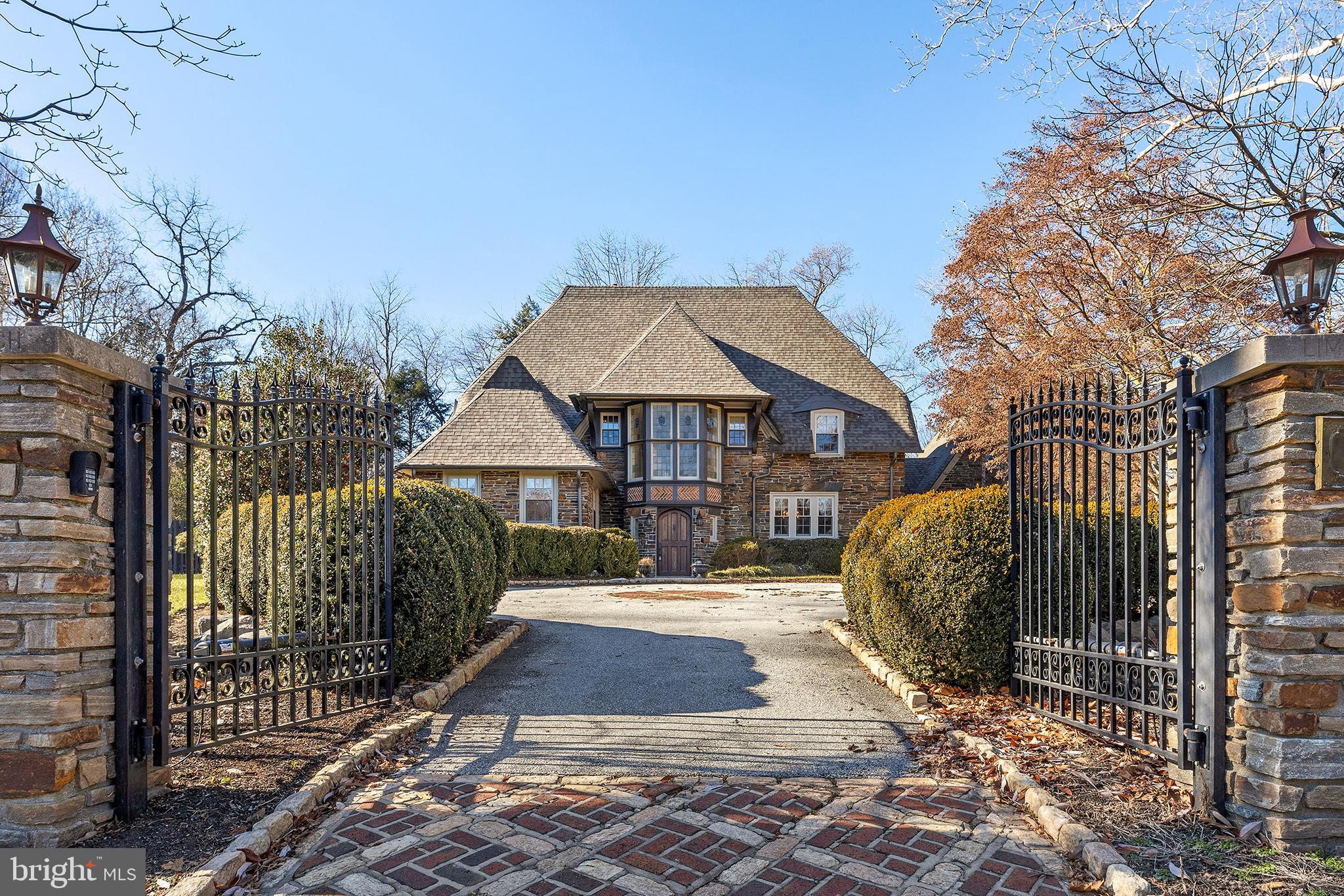 If you appreciate charm and class with fantastic upgrades and fixtures, then this 1920 s English Tutor home is a must-see. Enter through the gated driveway with a classic cobblestone courtyard with parking for at least 6 cars. The driveway continues around the side of the house to a 2 car garage with a rear entry and even more open space. The interior of this home has been updated and meticulously maintained, including a large 2-story addition in the rear that accommodates a modern open kitchen and great room with a built-in movie screen and projector on the first floor and an incredible owners suite on the second floor. As you enter through the original hardwood door into the foyer, you are immediately greeted with a formal living room to your left with a gas fireplace and entry into a salon room, filled with natural light and perfect for an office. A lovely glass door in the living room leads to the garden area. To the right of the entry is the formal dining room with floor-to-ceiling windows. Through the service pantry with laundry room, is the large eat-in kitchen and family room with tray ceilings and a projector system for movie nights. Oversized French doors from the kitchen eating area lead out to the spectacular rear yard with a flagstone patio. The mudroom off the service pantry hall leads to the garage and also to guest quarters above the garage, perfect for an Au-pair or a guest suite. Up the main stairway, you'll see the 4 original leaded glass windows that exuberate old-world charm. On the second floor is the large owner's suite with 2 walk-in closets, a gas fireplace, and an extremely spacious bathroom with double sinks, vanity, extra-large glass shower, and jetted tub. Another en-suite bedroom, plus 2 additional bedrooms and a full hall bath complete the second floor. The third floor has an abundance of space, perfectly suited for additional bedrooms and a large home office. A full hall bathroom and a walk-in closet are also on the third floor. The full basement features a large finished portion, a kitchenette, cabinetry, and sink as well as an abundance of unfinished storage space. This home also features a home generator that covers all of the essential elements to keep you comfortable. This impressive home is a short distance to the train and Suburban Square.