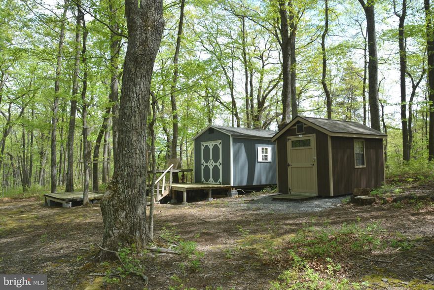 Private access (gated) to get to the  10 acre and 5 acre lots.  Take the gravel lane (gate is not locked) for about the length of 2 football fields to where the land begins.  This private lane ends at the land.  There are 2 nice utility sheds and an outhouse facility!, next to a campsite. (The firewood stays)  The land is nicely wooded with tall hardwoods.  There is an ATV trail along the left edge of the property that takes you to the rear 5 acres.  The land is slightly “rolling” surrounded by woods. There is a seasonal mountain view and dry creekbed  This is Fall Run Forest and falls under the guidelines of the Great North Mountain Wilderness community.  Both of the lots have recorded septic permits from the Health Dept (have to be updated).  If you love camping, hiking, hunting, you will definitely want to visit and walk the property. Walking the land is really the best way to appreciate what is offered. The perimeter is marked with 3’high metal stakes. This one is really priced to sell.
