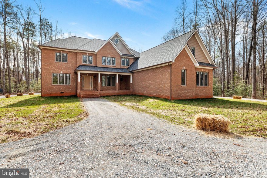 Experience unmatched tranquility and luxury in this stunning country retreat, offering 6 bedrooms, 4 full baths, and 2 half baths. Perfectly blending elegance and comfort, this home is ideally located near Goochland’s premier golf amenities. As you arrive, the inviting deep porch, breezeway, and adjacent carriage house set the tone for the serenity that awaits. Step inside to a sunlit foyer featuring white oak hardwood floors, intricate moldings, and modern finishes. The central staircase and formal living room are beautifully showcased by an indoor balcony, complete with a striking stone fireplace and views of the surrounding landscape. The living room's oversized windows frame picturesque scenes of the outdoor patio, adding to the home’s charm. At the heart of this residence is a sophisticated kitchen, complete with quartz countertops, custom solid wood cabinetry, and space for your preferred appliances. The bright breakfast nook is perfect for enjoying peaceful mornings. On the main level, a luxurious primary suite awaits, featuring a spa-like bathroom with a freestanding solid tub and it's own private deck access. Upstairs, an additional primary suite offers the same opulent amenities. Heated floors enhance the kitchen and bathrooms, adding extra comfort. This home also includes a prewired switch panel for a 22KW propane standby generator, a game room with a mini bar, and dedicated office space. Located just minutes from Short Pump, Wegmans, VCU Medical Center, and several premier golf clubs, this private oasis offers the perfect balance of seclusion and convenience.
