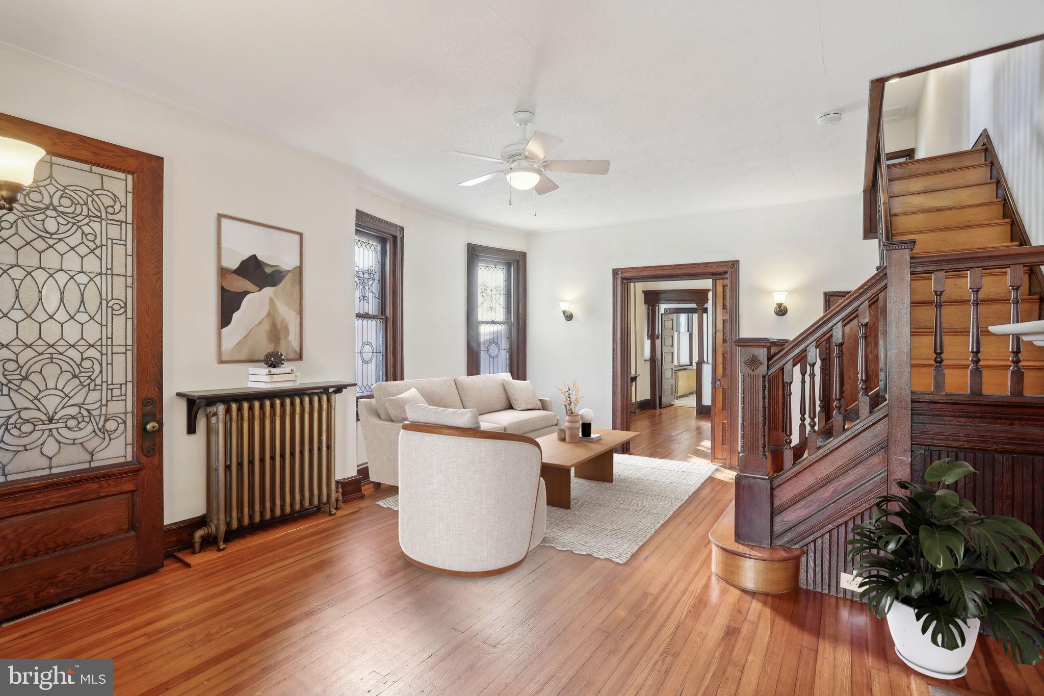 This charming completely renovated two-story semi-detached brick row home offers a blend of classic character and modern upgrades. Upon entering, the fenced front yard and inviting porch create a welcoming atmosphere, perfect for morning coffees and chatting with neighbors. Step inside to be greeted by original tiled floors and wood wainscoting, leading to an ornate leaded glass entry door. The living room is a true showcase of craftsmanship, featuring original built-in seating, intricate wood trim, and stunning leaded windows. A cozy fireplace, hardwood floors, and an ornate wooden staircase add to the charm, seamlessly flowing into the dedicated dining room, complete with additional built-in cabinetry. The heart of the home is the recently renovated kitchen, boasting stone countertops, a breakfast bar, ample cabinetry, and sleek stainless steel appliances. Adjacent to the kitchen, the laundry room offers a washer and dryer, additional cabinetry, a sink, and counter space for convenience. An updated half bath is also located here, along with a back staircase leading to the second floor. Step outside to the expansive deck and backyard, a perfect setting for entertaining. Upstairs, the second floor features four spacious bedrooms, all with original hardwood floors. The primary bedroom boasts a decorative fireplace and bow windows that allow for tons of natural light. A second bedroom also has bow windows and a wooden built-in closet. The well-appointed hallway bathroom with both a shower and separate bathtub, quartz countertops, double medicine cabinets, and ample storage. The lower level is partially finished and offers additional living space or storage. Recent upgrades include a renovated kitchen, half bath, and laundry room, a new electrical system, boiler, water heater, and roof (2017), a full bathroom renovation and new mini-split A/C (2020), and a fresh silver coat for the roof (2024).