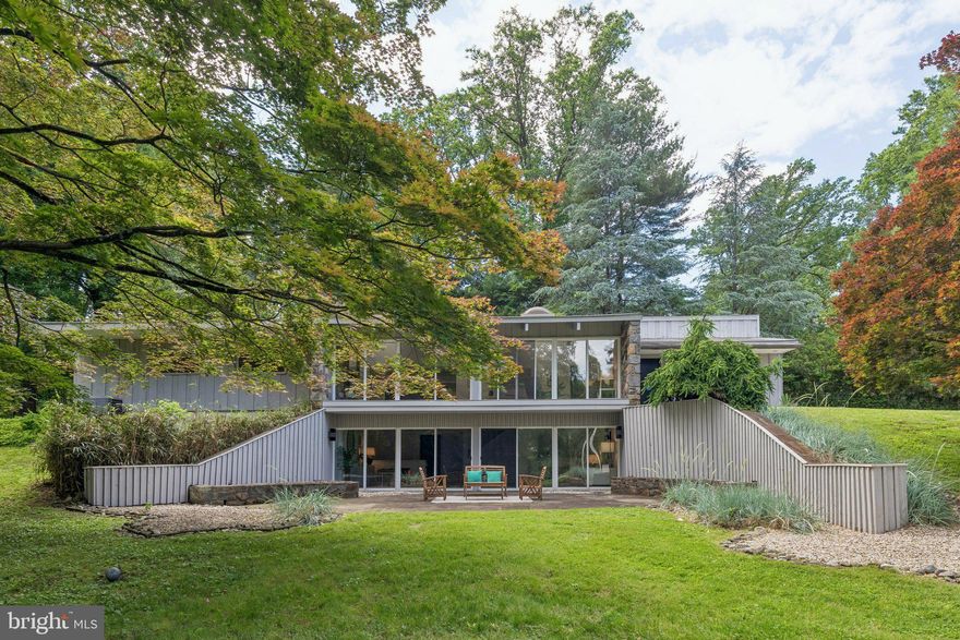 Set at the cul-de-sac end of highly sought-after Monk Road, this custom-designed Mid-Century Modern residence offers striking architecture, exceptional privacy, and tranquil wooded surroundings. Backing to a scenic glen and enveloped by mature trees, the property enjoys peaceful views and a rare sense of seclusion from its elevated position.
The home showcases the clean lines, dramatic scale, and seamless indoor-outdoor connection characteristic of Mid-Century design. Soaring ceiling heights define the main living spaces, while expansive walls of glass fill the interior with natural light and frame views of the surrounding landscape. Freshly painted throughout, the home offers bright, sun-filled interiors with a warm and inviting atmosphere.
A raked Japanese-inspired rock garden with scattered succulents and native plantings further enhances the property's serene setting, complementing the surrounding landscape and architectural character.
Offering four bedrooms and two and one-half baths, the home has been thoughtfully maintained over the years. The spacious family room features a built-in wet bar and opens directly to a private terrace, creating an ideal space for entertaining or quiet relaxation. Abundant closet space throughout, along with a large storage room for garden tools and seasonal items, provides exceptional functionality.
Additional highlights include a fenced yard, carport parking, whole house fan, central air conditioning, oil heat, fresh landscaping, and a newly refreshed interior.
Architecturally distinctive and exceptionally well sited, this is a rare opportunity to own a custom Mid-Century Modern home in one of the area's most coveted locations.