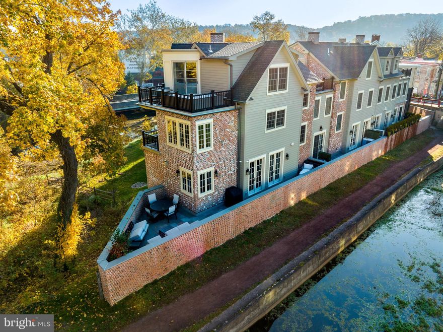 Water Front Panoramic Views!! Introducing The Falls at New Hope 2023 Excellence Award Winning: A Masterpiece of Luxury Living! 
Nestled in the heart of New Hope, this Custom New Construction Luxury Townhome Community is a pinnacle of opulence, seamlessly blending history and nature with stunning architectural detail. Overlooking the Aquetong Creek and New Hope's renowned Canal Path, it offers breathtaking, unobstructed views of the canal, making every sunset a spectacular event. This property, truly a once-in-a-lifetime opportunity, is a living experience that combines the charm of history and the beauty of nature, all while being just a stone's throw away from New Hope's vibrant restaurant row. This exquisite 4-bedroom, 4.5-bath, 4-story townhome has been meticulously upgraded with top-of-the-line high-end finishes, boasting exceptional features such as an elevator for convenience and an oversized 2-car garage for added luxury. As you enter this architectural beauty, you'll find the ground level featuring a spacious bedroom with a luxurious ensuite bathroom and ample closet space. This versatile space can be transformed into your personal fitness center or studio, tailored to your unique lifestyle. Ascending to the next level, you'll be greeted by an expansive open floor plan adorned with white oak flooring and recessed lighting throughout. Stunning high-end lighting fixtures and a magnificent floor-to-ceiling black marble fireplace adorn the spacious living room, creating a captivating focal point. The gourmet dream kitchen is equipped with modern white and dark custom cabinets, a large center island for social gatherings, and a beautiful mosaic tile backsplash. The adjacent dining room, with its elegant French doors, opens to a patio for year-round grilling and entertaining, offering splendid views of the property. Just off the kitchen, a elegant sitting room awaits, perfect for relaxing and reading. The primary bedroom, located on the floor above, is a sunlit sanctuary with an abundance of large windows, allowing natural light within the room. The primary bathroom epitomizes luxury, boasting a soaking tub, black marble glass shower, and exquisite gold fixtures and lighting sconces that create a spa-like experience. The primary suite also features a spacious custom closet and a private balcony, perfect for enjoying your morning coffee or a good book. The top floor of this exceptional townhome is a paradise for relaxation. The loft area is equipped with a wet bar and an outdoor patio, ideal for entertaining guests. This floor also conveniently features a bedroom and a full bath, ensuring your guests' utmost comfort. Downtown New Hope, nestled in the heart of historic Bucks County, offers the very best in restaurants, shopping, and events—all just minutes away. Don't miss the opportunity to own this luxurious townhome in the heart of New Hope, where luxury living meets breathtaking natural beauty. Your dream home awaits at The Falls at New Hope.  A Ralph C Fey Architects,  AIA Bucks County award winning development.