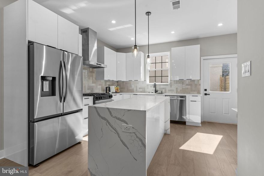 Welcome to 1321 N 2nd Street a brick-front masterpiece in the heart of Olde Kensington. This four-bedroom, two-and-a-half-bath home has been expanded with an additional level of living space, a full roof deck with 360-degree views of Center City Philadelphia, and luxury finishes throughout. The main level boasts 9’ ceilings, recessed lighting, and hardwood-style flooring flowing through a spacious family room with a custom accent wall and electric fireplace. A dedicated dining area leads into the chef’s kitchen, where sleek 36” white cabinetry pairs with a calacatta quartz waterfall island, high-end appliances, a motorized microwave, custom backsplash, chimney hood, matte black hardware, and statement pendant lighting. A half bath with touch-screen mirror and access to a massive backyard designed for entertaining complete this level. Custom open-riser stairs with night lighting and metal railings lead to the second floor, featuring two generously sized bedrooms, a full bath with a floating double-sink vanity, and a laundry room with built-in cabinetry. The third floor offers a full additional bedroom plus a private primary retreat highlighted by a custom trim accent wall, custom closets, and a spa-like bathroom with soaking tub, wet bed area, and oversized rain shower. This level also includes a stunning wet bar with a calacatta quartz waterfall counter, custom sink and shelving, and a built-in mini fridge—perfect for entertaining before heading upstairs. Continue upward to the roof deck, where you’ll enjoy breathtaking 360-degree views of Center City Philadelphia. A fully finished basement adds even more versatile living space, ideal for a home office, gym, or media room. This property truly has it all—modern design, thoughtful upgrades, and an unbeatable location. Make your appointment today.