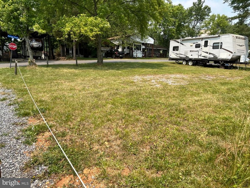 Bring your vision of PARADISE to this wide open land lot in popular RIVER BEND PARK! The level lot is in Block 26, where properties are more spacious. You’ll have extra PRIVACY thanks to the CORNER location. Road frontage on two sides makes it easy to pull vehicles straight through. Water, electric and sewer hook-ups (no need for pump-outs!) are included in the annual dues. Terrific LOCATION in the center of the community, very close to the swimming pool, club house, restaurant and ranger station. Convenient access to the BOAT RAMP gives you miles of deep water POTOMAC RIVER. The sale includes a 2011 26-FOOT WILDWOOD TRAILER that sleeps seven, has a tub/shower combination, and a kitchen with stove, oven, refrigerator and double sinks. The interior is very lightly used and offers impressive STORAGE in closets and cabinets. River Bend is a gated seasonal campground, April 1 – November 1, with the best FIREWORKS around and a busy calendar of social events. Come join the FUN! …NOT in the flood zone. …CASH ONLY.