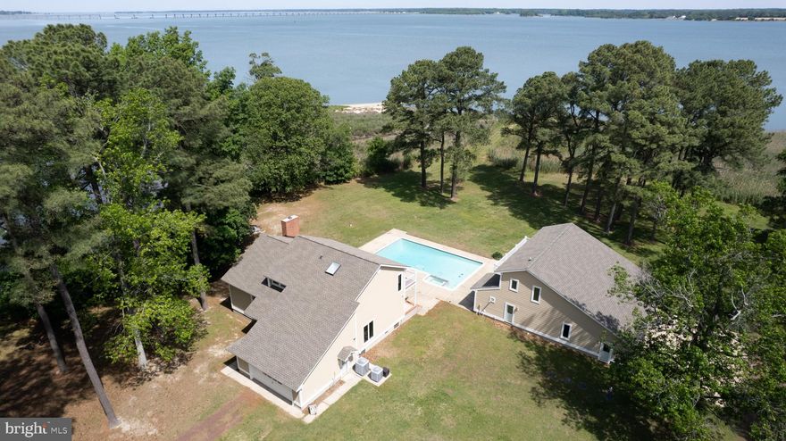 This beautifully maintained 3/4-bedroom home situated on 4.3 +/- acres offers panoramic wide-water views and exceptional outdoor living.  Updated kitchen with granite countertops and a primary bathroom with steam shower.  This home blends comfort and style. Enjoy cozy evenings in the sunken living room with a classic wood-burning fireplace.
Recent upgrades include a new roof, siding, and HVAC system for peace of mind. Recent BAT septic system.  Outdoor amenities abound, including a 20’ x 40’ heated in-ground pool with spa, a spacious 2-story deck, and a screened porch perfect for relaxing or entertaining.
The property also includes an attached garage plus a conditioned, detached 3-bay garage with a pool house and a second-story guest suite. A large oil-fired generator ensures uninterrupted power.  Surrounded by mature pine trees, this home is a private riverside haven just minutes from Cambridge.