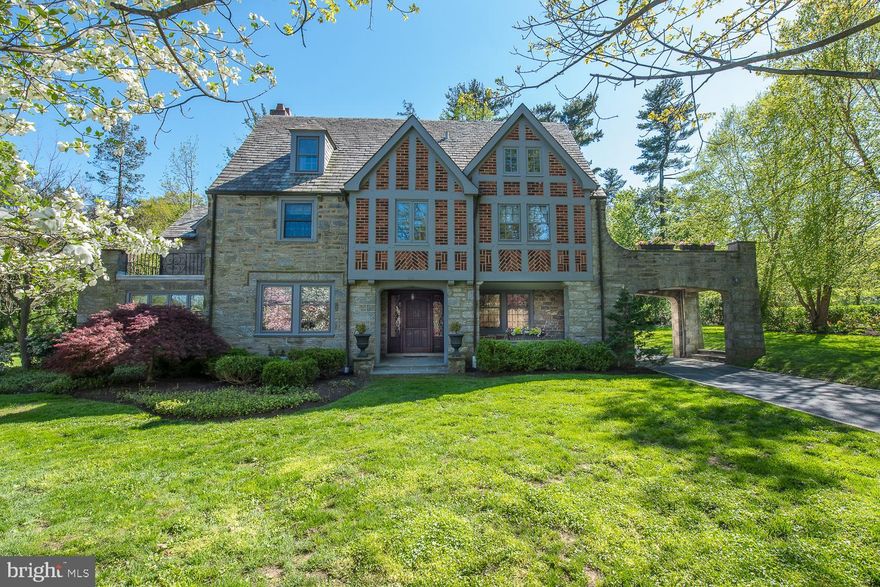 Move right into this stately stone and brick Tudor gem with beautiful slate roof. It is situated in the premier estate section of Merion on a pretty street graced by mature trees and landscaping. Exuding character and  old world  charm, it is truly a dream home for the discerning buyer. Walk through the stone pillars, under the port-cochere to the slated entrance where the front door is flanked by leaded glass windows. Enter the Center Hall showing architectural detail and hardwood floors which continue through-out most of the house. Enjoy family meals in the elegant Dining Room featuring built-ins, recessed lighting and pretty views of the outside. The Kitchen is a chef s delight and is highlighted by stainless appliances with gas cook-top, a double oven, a warming drawer, granite counters, ceramic back-splash, center island, a radiant floor, Wood-Mode cabinets, radiant heated floor and back stairs. There is a Breakfast Room accented with a whimsically tiled window sill and a Mud Room which exits to the driveway. The formal Living Room is graced with an artistically created tiled fireplace and recessed lighting. Relax in the spacious Family Room which is light-filled and boasts crown moldings, built-ins, a wet bar with refrigerator, tile floor and a handsome stone fireplace. The Loggia is airy and bright with French doors and windows looking out and commanding a beautiful scene of the private slated patio, lush landscaping and stone Carriage House. A Powder Room and guest Closet complete the 1st floor. The staircase is distinguished with wrought iron balusters and ascends to the 2nd level. Curl up with a book in the stunning wood paneled Library flaunting leaded glass windows, an arched ceiling and masterfully crafted bookcases. The cozy Master Bedroom suite consists of a Bedroom, Dressing Room with attractive built-ins, cedar closet and a beautifully tiled master Bathroom with marble counters and enclosed tub and steam shower. There is a Bedroom en suite with Bathroom, closet and picturesque Balcony. Two other Bedrooms finish this floor, both with terrific closet space and another Balcony. They share a pretty Bathroom with vanity and enclosed shower accented with an intricate design. There is a hall linen closet. Generously sized 5th and 6th Bedrooms are located on the 3rd level with ample closets and storage space. There is a Bonus Room and an updated hall Bathroom. The finished Basement has hardwood floors and provides more living space. There is a Laundry, a 2nd Powder Room, another spacious room, a bar and closets. The Carriage House has a 2 car Garage with potting shed, lots of storage and rooms that can be converted to office, studio, or apartment space.   Award winning Lower Merion Schools! Walking distance to school, shops, dining and transportation.