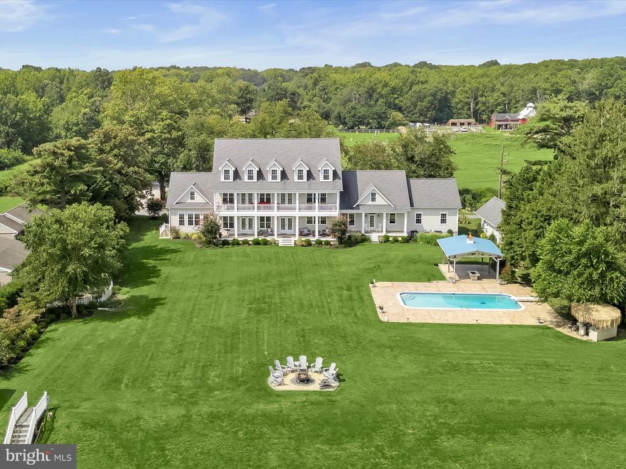 Welcome to 235 Bay Front Drive, a magnificent Chesapeake Bay waterfront property nestled at the end of a private lane with peaceful views from the front of the historic Flanigan horse farm. This stunning 1.3 waterfront property is a stone’s throw to Gibson Island. Just built in 2017, this substantial property boasts seven bedrooms and eight and one-half bathrooms.  
With amazing Bay views from the minute you open the door, ascend the front steps to a welcoming front porch, entering a large two-story foyer opening to a spacious living room. Enjoy the gourmet kitchen offering an expansive island with plenty of counter seating coupled with a kitchen table/nook and wet bar. The kitchen opens to a large dining area making for family relaxation and gracious entertainment.  Expansive Bay views abound from the kitchen and living room, both of which open to a fabulous open porch spanning the waterside house of the house. 
A primary bedroom with exquisite bath is on the main level, along with a second ensuite bedroom. An office with incredible Bay views, a half bath, laundry room and direct access to the three-car garage top off the main level.
Ascend the stairs to a fabulous entertainment room with a built-in bar, pool table area, and lounging space overlooking the Chesapeake Bay and opening to an expansive outdoor open porch with further exquisite Bay views and sunrises.  Four ensuite bedrooms complete the upper level.
Descend to the lower level to a game room, a den/cigar room, a stunning conditioned wine room, work out and gym area, a sweet reading nook, a secured area for storage, coupled with many additional storage spaces. 
An attractive detached guest cottage matching the house exterior includes a living room, kitchenette, bedroom, full bath, and washer and dryer. A three-car garage is connected to the house with plentiful parking in front of the house.
This property has it all, including lush landscaping, an in-ground salt swimming pool, a tiki bar, a covered entertainment area, and an outdoor wood-burning fire. The expansive yard overlooks the Bay with a sandy beach, and there is an approximate 190-foot pier with a covered electric lift and freshwater spigots and an additional side pier, all great for fishing, crabbing, and just plain relaxing and enjoyment of the Chesapeake Bay!