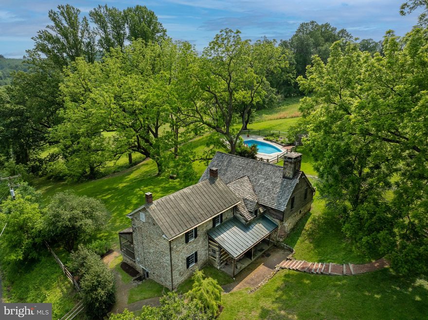 Welcome to 880 County Park Road. This 10+ acre property hosts one of the most unique and spectacular views in the Warwick Furnace Valley. It is situated near the top of County Park Road with expansive views from the entire property. The house contains 4 bedrooms and 3 full bathrooms (1/2 bath in Garage/Barn) as well as a great room, living room and dining room with exposed beams and hardwood floors throughout. The great room also contains a large stone walk-in fireplace and a beehive oven! Another unique aspect of the home is the metal bridge that connects the circa 1751  house to the addition (1910 and 1980). You might also enjoy the hot tub off of the primary bedroom, the large pool and pool deck with AMAZING views of the surrounding land, a dis-used tennis court that can host pickleball and basketball and lastly a detached barn with many possibilities! The newer barn has a first floor 2 car garage and second floor multipurpose room. The entire building is heated, insulated and has a 1/2 bathroom on the second floor! Leave it as a barn or reinvent this space as an office, garage, extra storage, yoga studio, art studio or much much more.  The entire property along with many surrounding properties are conserved with Natural Lands Trust to protect their natural beauty and purpose. Do not miss this opportunity to acquire one of Chester County’s most beautiful homes!