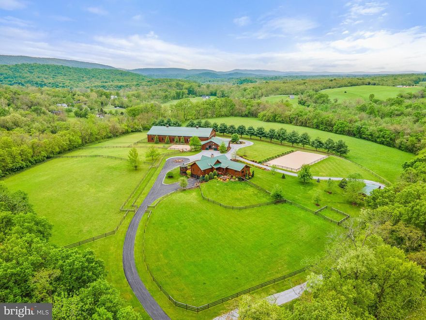 Dressage Heaven with style, beauty, and function – no detail has been overlooked to create the ultimate oasis for both you and your equines at Westwind Farm. This 10+ acre equestrian estate is a must-see.  The Residence:  The stunning 3BR/3.5BA log home was designed to bring in the light and create a seamless feel from indoors to out. The open concept in the main living/kitchen/dining area with soaring ceiling, wood beams, and huge gas fireplace with stone surround is the perfect space for family or entertaining.  Numerous windows and multiple decks provide sweeping views and yet more space for gatherings or a simple respite with the morning coffee. This home is replete with custom features throughout - custom wood mantle, claw foot bathtub, frosted glass privacy doors, a convertible au pair suite, and so much more.  For the Equestrian: WOW. Horse enthusiasts will be impressed with the workmanship, layout and attention to detail evident in all aspects of the horse accommodations and riding facilities. Without question, every consideration has been made. Ride 24/7 in all weather conditions in an impressive 66' x 132’ insulated indoor riding arena with mirrors and bluestone, Eurofelt custom blended sand footing.  As if that wasn’t superb enough, there’s another arena outdoors - 66' x 132' (GPS/laser bluestone/sand).  The immaculate 4 (12x12) stall barn offers a heated wash stall with h/c water, indoor and outdoor fans, automatic waterers with meters, and a climate controlled tack room with separate laundry and kitchenette. Four fenced pastures and 3 paddocks make for easy and flexible turnout or layup options.  The Property:  The majority of the property is contained inside 5000' of maintenance-free 3-rail brown vinyl fencing run with hot wire and a perimeter entry, enhanced by underground irrigation and CCTV systems. For storage and equipment, there’s a 26' x 26' metal garage, and a climate controlled workshop with water and electric. Central A/C and Heating Features: 2-stage heat pump reverts to gas heating. 1000 gallon buried propane tank. Generac: House, Barn. Construction Materials: log, log siding, and metal roofs on all buildings.  Location:  The quaint and historic town of Shepherdstown is a delight for shopping, dining, and sightseeing, and is home to Shepherd University. A very short drive will take you to Marc Train and Metro Rail stops, the lovely town of Sharpsburg MD to the North, and Harpers Ferry and Loudoun County to the South. Both Dulles Intl. Airport and Baltimore Washington Airport are less than an hour and a half away. Westwind Farm is nestled in an area which provides access to amenities without sacrificing privacy and enjoyment of the region’s natural wonders.