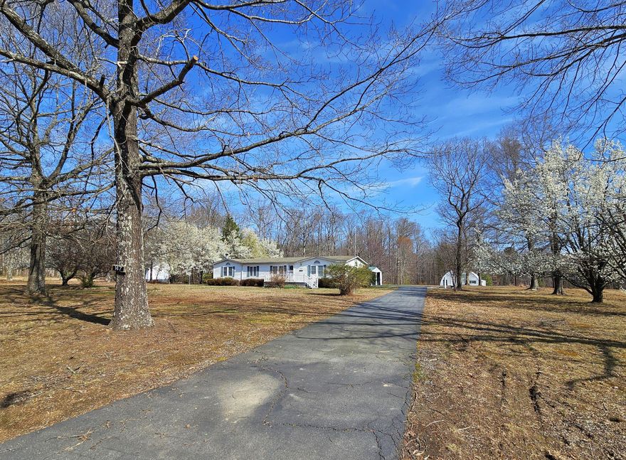 Nestled in a serene, rural setting, this charming ranch-style manufactured home offers a perfect blend of comfort and functionality. With over 1,800 finished square feet of thoughtfully designed living space, this residence features three spacious bedrooms and two full bathrooms, including a luxurious primary bath with a soaking tub and walk-in shower. Step inside to discover a warm and inviting atmosphere, highlighted by beautiful crown moldings and rich wood floors. The family room, conveniently located off the kitchen, is perfect for gatherings, while the formal dining area sets the stage for memorable meals. The country-style kitchen boasts an island, ample cabinet & pantry space, and modern appliances, including a built-in microwave and dishwasher, making meal prep a delight. Outside, the expansive 3.4-acre lot offers a peaceful retreat with a mix of open space and wooded areas, perfect for outdoor activities or simply enjoying nature. The property features an enclosed porch, large, covered patio, and outbuildings, including a large Quonset hut with an oversized garage door - perfect for hobbies &/or additional storage. With a rural location that provides tranquility yet is just a short drive from local amenities, this home is ideal for those seeking a peaceful lifestyle without sacrificing convenience. Enjoy the benefits of a paved driveway and ample parking, including a semi-attached carport. This property is not just a house; it's a place to create lasting memories!