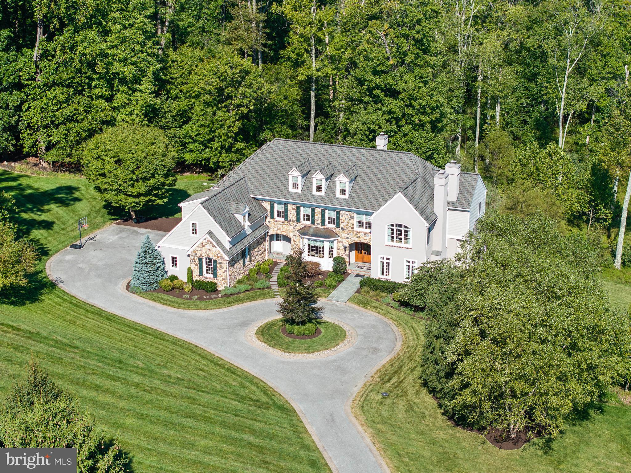 Be prepared to be "wowed" by this stunning, custom built estate home, nestled on 9 private acres in the heart of bucolic Malvern in "Spring Meadow Farm." The special parcel was originally owned by the Tory Burch family and the original Georgian Mansion and farm still stand as a neighbor's house. This is the first time that 3 Autumn Meadow Lane has been listed for sale. The property is located in the rear of the community, tucked away from other houses and public roads. This gorgeous, 5-bedroom, 6-bathroom home with a finished walkout lower level is the epitome of luxury and comfort.
As you meander down the long driveway with iconic white fencing, you will be in awe of the curb appeal of the property with a circular driveway and a natural stone façade which sets the stage for the elegance that awaits inside. Step through the grand entrance into a spacious foyer, flanked by a formal dining room with beautiful millwork and wainscoting and a butler's pantry with wet bar, perfect for hosting elegant dinners and holiday gatherings. Across the foyer, the living room invites you in with its cozy gas fireplace, ideal for relaxing evenings.
The open floor plan seamlessly connects the family room, complete with gas fireplace, breakfast room with vaulted ceiling, and gourmet kitchen, creating a perfect space for both everyday living and entertaining. The kitchen is a chef's delight, equipped with top-of-the-line appliances like Sub Zero refrigerator, an 8 burner commercial-grade Wolf range, Wolf warming drawer, 2 islands, ample counter space, and custom cabinetry. Just off the breakfast room with a vaulted ceiling, you'll find a slate patio, an idyllic spot for al fresco dining and enjoying the serene surroundings.
The home boasts soaring 9.5' ceilings, built-in speakers, and exquisite Brazilian cherry hardwood flooring throughout, enhanced by detailed moldings and wainscoting that add a touch of charm and sophistication. The handsome office, adorned with rich wood paneling, a gas fireplace and built-in shelving, offers a quiet retreat for work or study. Two half baths, a mudroom with built-in cubbies and a 3 car attached garage complete this floor. The second level features 5 bedrooms and 3 full bathrooms. The primary suite includes a huge bedroom with tray ceiling, sitting room, 2 walk-in closets with custom closet system, and a luxurious primary bathroom, with dual vanities with marble countertops, a large stall shower with frameless glass enclosure, a jetted tub and separate water closet. There are 2 bedrooms connected by a jack and jill bathroom and an additional bedroom suite. The 5th bedroom could also be used as a playroom or in-law suite. There is a second floor laundry room and the back landing is spacious and makes a great homework station. The third level features a huge unfinished space that presents many possibilities. The back staircase conveniently leads to the kitchen.
The finished walk-out basement with gas fireplace and bathroom provide an additional living space, making it perfect for a home theater, gym, teen hangout or game room. Conveniently located near the Septa/Paoli Train Station, the PA Turnpike and Route 202 for easy access to NY, Phila. or DC. Nearby shopping/restaurants at Whole Foods, King of Prussia Mall and quaint downtown Malvern. This 9 acre country estate combines luxury living with the tranquility of a private, expansive property.