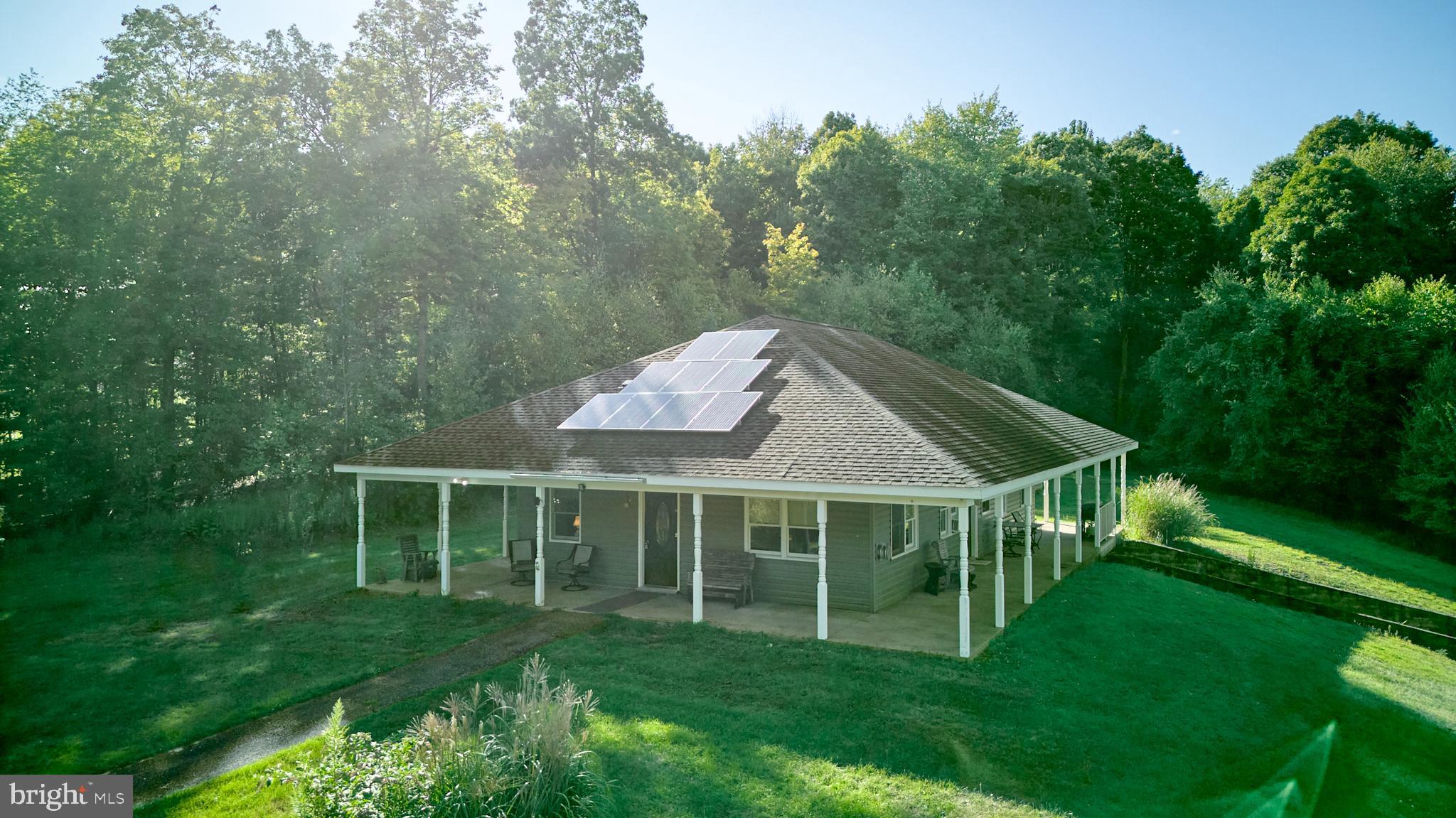 Looking for a peaceful escape? Check out this ranch home with stunning views from the wraparound porch. It includes an owner's suite, an additional bedroom, and a full bath. Nestled on 49.56 wooded acres, this off-grid property features solar panels and propane heating. The open floor plan connects the kitchen, dining, and living room seamlessly. The property also includes a 30x40 pole barn/garage and two small cabins. Great hunting. 15 minute drive to PSU and State College.