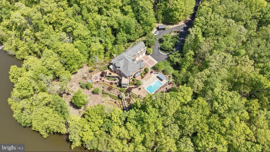 An extraordinary waterfront home set on five private, wooded acres with an impressive 392 feet of shoreline. This custom all-brick Renaissance estate spans nearly 9,000 square feet, offering sweeping water views from all four levels and timeless architecture, refined interiors, and a resort-style outdoor living space.

From the moment you arrive, the setting feels like a secluded retreat. Mature trees frame the home, creating a sense of privacy and tranquility rarely found with this level of waterfront access. Expansive outdoor living spaces—including seven balconies and porches—invite you to take in the water from every vantage point, while the sunroom, Trex deck, and stone patio create effortless transitions between indoor and outdoor living.

At this breathtaking waterfront resort, you’ll find an in-ground pool and separate hot tub that overlook the lake, while a private dock provides a permanent parking space with direct access for boating, fishing, and peaceful evenings on the water. The lake becomes a natural extension of daily life—perfect for morning coffee at sunrise, afternoon adventures, and unforgettable sunsets reflected across the water.

Inside, the home was thoughtfully designed to balance grand-scale entertaining with comfortable everyday living. A glass-walled elevator offers convenient access to multiple levels, adding both function and architectural interest. The residence features six en-suite bedrooms, each with its own private balcony—an exceptional design detail that ensures every bedroom feels like a private oasis overlooking the water.

The recently updated gourmet kitchen is as beautiful as it is functional. Outfitted with Café appliances, double dishwashers, a beverage refrigerator, and an expansive butler’s pantry with wine storage, the space is designed to accommodate gatherings of any size. Whether hosting intimate dinners or large celebrations, the flow between the kitchen, sunroom, garden room, and surrounding outdoor spaces makes entertaining seamless and memorable.

Upstairs and throughout the home, water views create a constant connection to the landscape. Natural light pours through well-placed windows, enhancing the home’s architectural lines and highlighting the peaceful setting beyond. Additional luxury investments include extensive landscaping and hardscaping throughout the grounds, along with a serene in-ground koi pond.

The walk-out lower level features nearly 2,200 square feet of fully-finished living area. The lower level offers a private bedroom with a full ensuite bathroom ideal for guests, extended stays or as an in-law suite. Entertainment is a breeze on this level thanks to the large recreation room, additional kitchen, powder room and theatre room. With direct access to the grounds and pool area, it functions beautifully as its own retreat within the home.

This is a rare opportunity to own a truly private waterfront estate where refined living, natural beauty, and thoughtful design come together in perfect harmony.