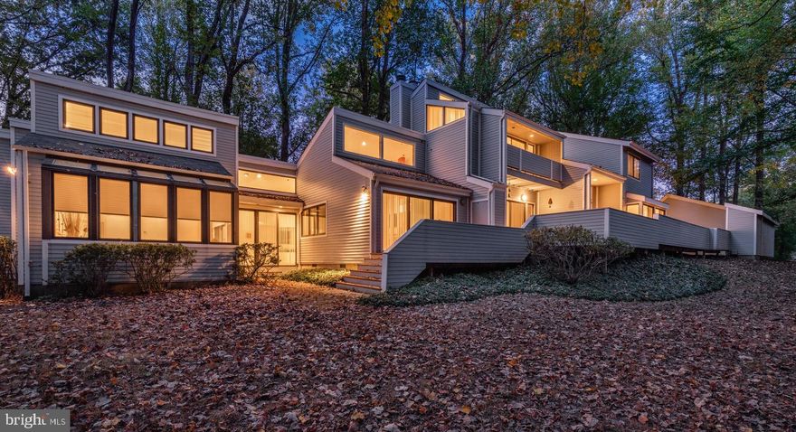 Listed on the market for the first time, 6908 Persimmon Tree Road is a unique architect- designed and owned custom contemporary residence on a one-acre wooded lot in Bethesda. The owners, a FAIA-recognized architect and a leading interior designer, have lovingly cared for and expanded the home since designing and building the residence from the ground up in 1976.

This stunning contemporary home with walls of glass is a one-of-a-kind residence that offers a truly unique living experience that seamlessly blends modern luxury with natural beauty. Set far back from the street and approached by a long driveway, the house has a more private front while unfolding amid soaring open spaces. The 700 square-foot carport with storage closet is set to side of the home to keep the focus on the main structure.

Clean lines, soaring ceilings, and an open-concept layout create a sense of spaciousness and light. The 4,600 square-foot home features four bedrooms, including two primary suites, 3.5 bathrooms and two separate home offices. A large renovated eat-in kitchen, separate dining room, formal living room and den complete the main living spaces. Recessed lighting can be found throughout the home. More than 2,500 square feet is located on the main level

Outside, there is 1,000 square feet of recently stained wood deck running the length of the first floor with access from every main-level room. The large, 6,000 square-foot useable level rear yard is wooded at the back of the property.

The main entrance is marked by a large two-story entry foyer with covered front porch. After food shopping, the entrance off the double car-port area can be used to enter the mud room/kitchen. The mud room with laundry and utility sink opens into the large modernist kitchen with floor to ceiling storage cabinets with custom built in shelves and drawers by Neff, 10-foot long serving island, separate wine refrigerator, microwave, oven, warming drawer, six-burner electric cook top and recipe desk area.

Beyond the kitchen is a main floor powder room, a formal two-story dining room with built-in cabinets and multiple living areas, including the living room and den, gallery area with built-in planter and office with large walk-in storage closet. The new primary suite sits at private section at the back of this main level. Both the large living room and family room with soaring ceiling, clerestory windows and built-in cabinets have fireplaces.

The first-floor large primary bedroom suite with soaring ceiling features a recently renovated five-fixture bath and large dressing area with natural light and built-in dressers, free standing tub, walk-in shower and clerestory windows. This area has its own mechanical system.

The top level includes three large bedrooms, including the original primary bedroom suite, a high sloped ceiling open play area with clerestory windows, the third full bathroom with adjacent linen closet and office space with built in cabinets. The bedroom suite features a bath, double vanity, dressing area with high ceiling, clerestory windows and balcony.

The finished basement includes a play area, storage and the main mechanical systems. The home has a Guardian alarm system. Schools are Bannockburn Elementary, Thomas W. Pyle Middle School and Walt Whitman High School.