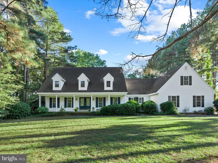 Welcome to 27671 Riverside Drive Extension in Salisbury, a charming Cape Cod retreat nestled on a private 1.24-acre lot surrounded by nature. A long driveway leads to an oversized side-entry garage, beautifully landscaped grounds, a covered front porch, and classic dormers that add timeless appeal. Step inside the two-story foyer, where a warm and inviting living room with a gas fireplace sits opposite a formal dining room ideal for hosting special occasions. The spacious eat-in kitchen features rich cherry wood cabinets with trim-topped finishes, a stylish backsplash, and a high vaulted ceiling over the dining area accentuated by a large window that frames serene backyard views.

Just off the kitchen, a comfortable family room shares a double-sided fireplace with a bright and airy sunroom, a perfect spot to relax with morning coffee or evening gatherings. From here, step out to the expansive deck and paver patio, thoughtfully designed for outdoor entertaining and enjoyment of the tranquil setting.

The main-level primary suite offers comfort and privacy, complete with an ensuite bath featuring a dual-sink vanity, soaking tub, and two walk-in closets. A convenient kitchenette and laundry area off the garage provide additional storage and functionality, complemented by both a full and half bath on this level.

Upstairs, you’ll find three additional bedrooms and a spacious bonus room that can serve as a second family room, home office, or fitness area,  offering flexibility for a variety of lifestyles.
This home combines classic design with modern convenience, all within a peaceful and private setting just minutes from Salisbury’s shops, dining, and amenities.