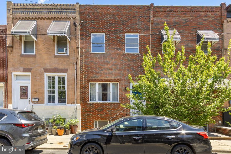 Lovely, Spacious 2-Story East Passyunk TownHome featuring restored and new oak hardwood floors throughout, a brick front with porch, and a tiled entry opening to a large living room with a wall-to-wall front windows providing abundant natural light. Beyond the living room is a formal dining room, a fully tiled first-floor bath with shower, and a sizable flexible room suitable for use as an office, recreation room, or additional dining area. The modern eat-in kitchen includes beautiful oak cabinets, a dishwasher, and brand-new oak flooring, and provides access to a rear yard suitable for grilling and gardening. The second floor offers an expansive rear bedroom (approx. 13' x 22') with a wall-to-wall closet and two floor-to-ceiling windows, a tiled hall bath with tub and shower, and two additional generously sized bedrooms with wall-to-wall closets. A very large basement (approx. 15'–16" x 57') offers ample storage, closet space, laundry area with washer/dryer, and mechanicals, and is ready for finishing or additional storage needs. This is one of the larger two-story townhomes in East Passyunk, in close proximity to East Passyunk Avenue shopping, restaurants, bars, Singing Fountain, the Acme/CVS shopping center, and the nearby Bella Vista area.