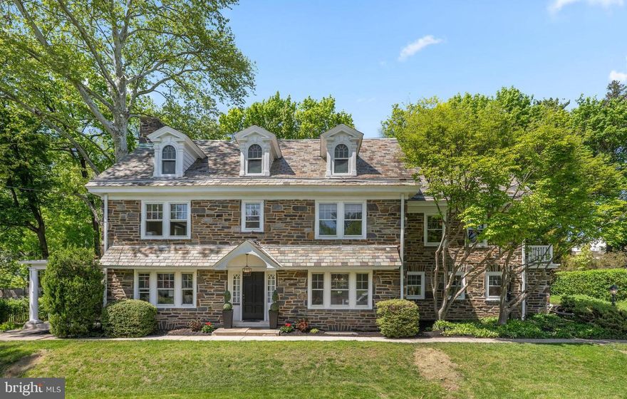 Built in 1929 for Henry Linvil and thoughtfully reimagined for today’s living, this stately stone Colonial seamlessly blends timeless character with a design-forward renovation. Set on a wide .4-acre lot, the home offers 5 bedrooms, 4 full baths, and 1 half bath across beautifully finished living spaces. A welcoming vestibule opens to a gracious, wide center hall. To the left, the expansive living room is anchored by a wood-burning fireplace and framed by French doors leading to a charming side porch—an ideal spot for morning coffee or quiet evenings. To the right, the formal dining room with classic chair rail detailing flows effortlessly into the beautiful, brand-new gourmet kitchen. Designed with both style and function in mind, the kitchen features a dramatic 9-foot island with quartz countertops, stainless steel appliances, double ovens, a Bosch dishwasher, Sub-Zero refrigerator, and a 5-burner gas cooktop—perfect for everyday living and entertaining alike. A mudroom with built-in bar and wine refrigerator, a convenient half bath with fun wallpaper and an attached two-car garage complete the main level. Upstairs, the second floor offers four bedrooms and three full baths, including a luxurious primary suite with a spacious bedroom, dual closets, and a beautifully renovated bath featuring an oversized shower with rain head, frameless glass enclosure, and double vanity. Additional bedrooms are generously sized—one with a bonus room—alongside a hall bath and a private bedroom suite with a charming clawfoot tub. A well-placed laundry room with barn door adds everyday convenience. The finished third floor expands the living space with a fifth bedroom, a full bath with tub/shower combination, and a versatile lounge or family room—plus a substantial carpeted storage area. Out back, a new slate patio sets the stage for effortless outdoor entertaining and al fresco dining. Central air conditioning installed in 2025. All this and a fabulous location, one mile to Suburban Square and close to the award winning Lower Merion High School. One of the listing agents has a financial interest in the property.