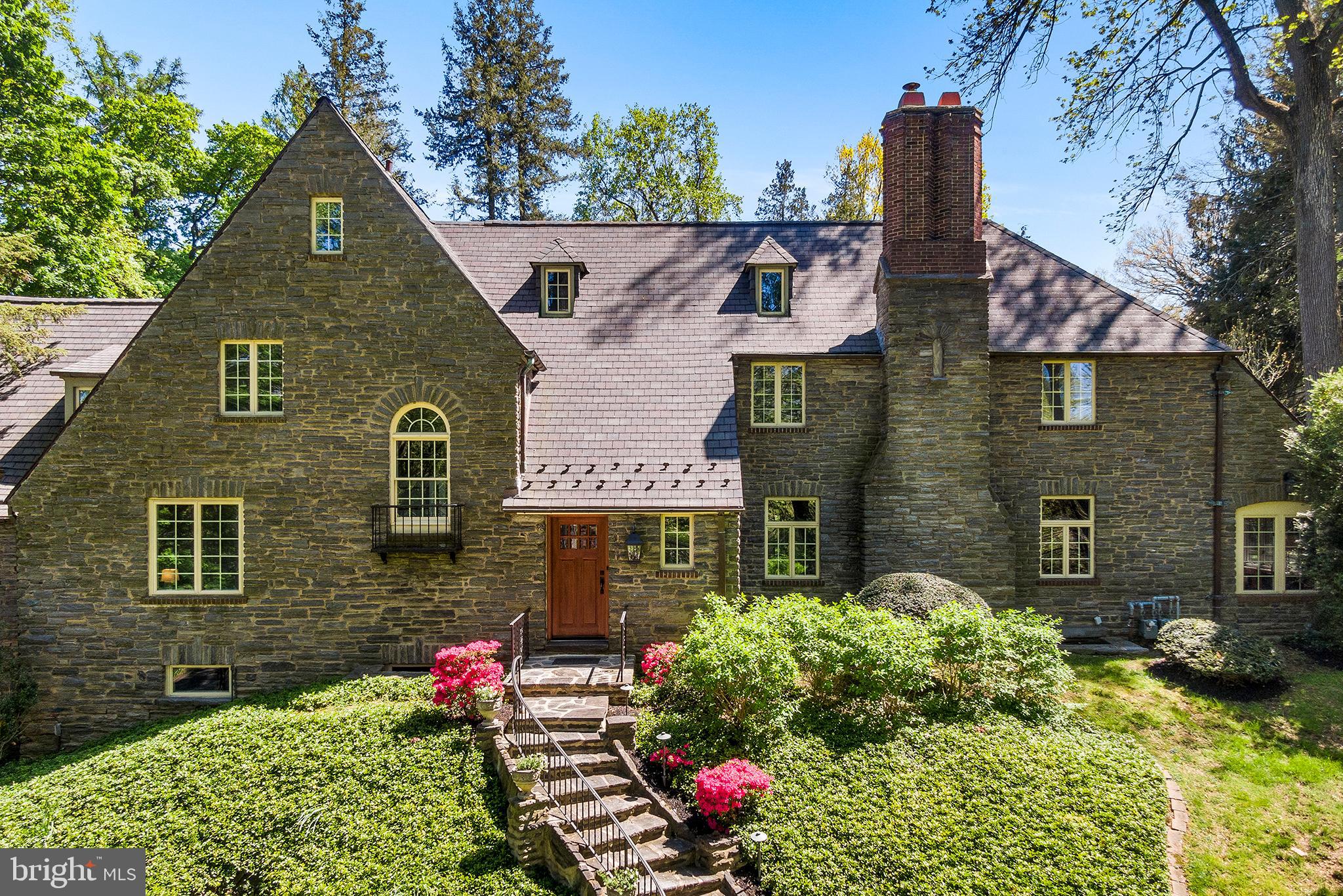 Drive up a circular drive to this J. Bedford Wooley designed elegant three story stone colonial with extraordinary architectural detail. Enter into a front-to-back center hall. To the right, find the the formal living room with stone detailed, working wood fireplace. Continue into the the library/den with a wet bar, perfect for entertaining. Take a step down into the sun room and take note of the stone walls, high ceilings, and abundant light brought in by the skylights overhead. The stone floored home gym grants access to the backyard patio to adore the well-maintained outdoor space. Retreat to the center hall and enter the French doors to the formal dining room with a 5-pane bow window. The open kitchen has a dining area, entrance to the connected greenhouse, and provides equal parts function and appeal. Deep white ceramic farm sink, black countertops, white cabinetry, and an island with Viking 6-burner stove top with griddle, dual ovens, and overhead built-in hood vent. Other high quality stainless steel appliances include a Sharp pull-out microwave, SubZero French door refrigeration and dishwasher. Rounding out the the main level, find a home office with two desk settings. Walk up the main staircase to the find the primary bedroom with abundant space and storage. Two walk-in closets, sitting area and attached bathroom with dual sinks, standing dual head shower, and vanity area. All bathrooms were renovated between 2002-2015. Two other spacious bedrooms with en-suite baths and a hallway walk-in closet can be found on this level. The third level features two additional bedrooms, one with a cedar wood closet, that share a hall full bath. The finished basement has the final full bathroom, a laundry room with two washers and two dryers, abundant storage rooms, and a walk-out exit to reach the attached two car garage.