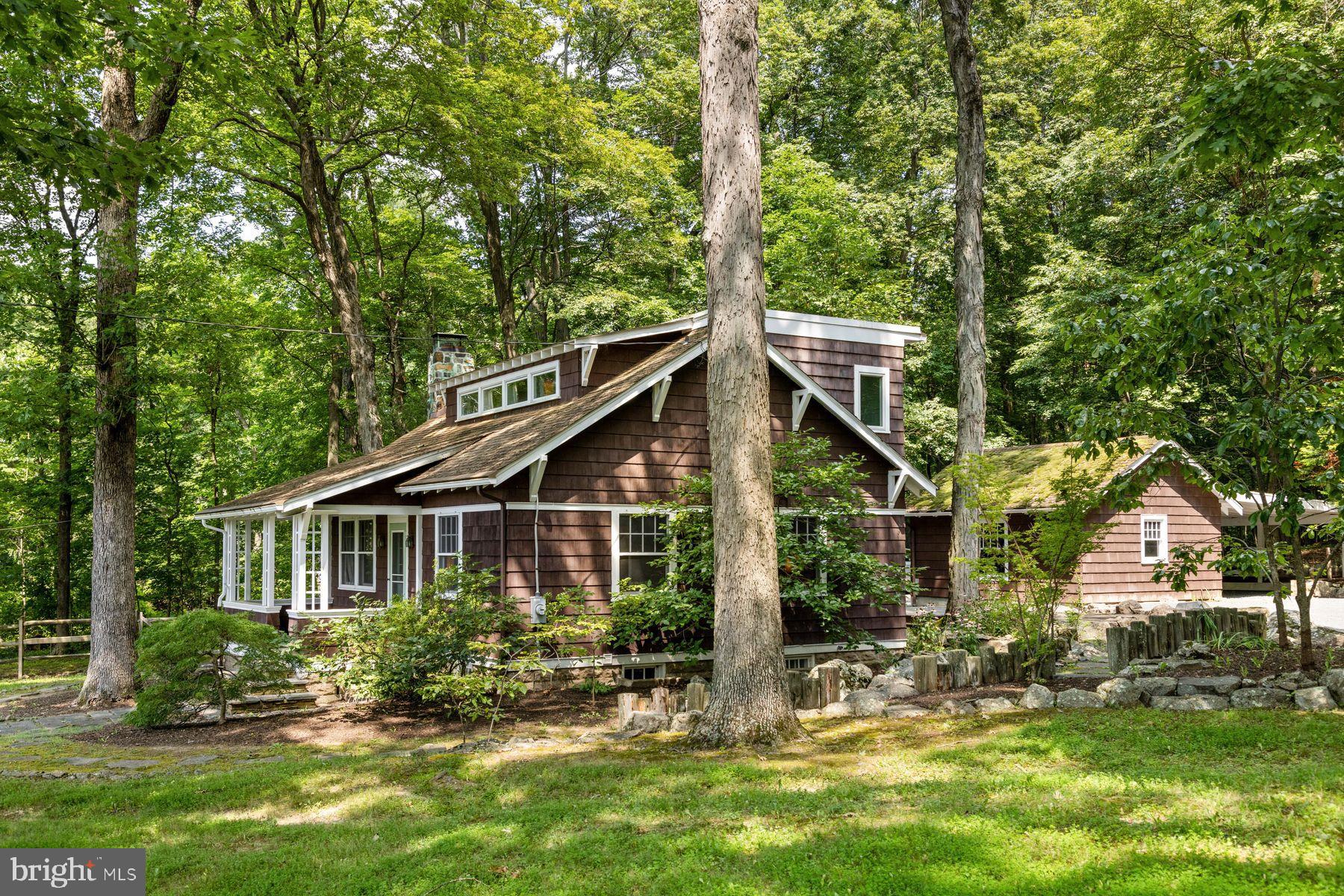 Nestled in a natural rural setting, this charming 1938 Arts and Crafts style bungalow offers a perfect blend of classic character and modern comfort. The park-like setting and Japanese-inspired cottage garden is tranquil and serene. The covered front porch welcomes you to step inside and discover a warm and inviting interior featuring solid hardwood floors, wainscoting, exposed beams and high ceilings. The bright living room is anchored by a wood-burning fireplace with hand-carved oak surround and mantel, perfect for gathering on chilly evenings, and flows nicely to the formal dining room with charming built-in corner cabinet. The country kitchen is efficient with built-in appliances, including a microwave and electric range, and substantial storage with period built-ins and traditional cabinetry. With three bedrooms and two full baths, including a primary bath with jetted tub, this home is designed for relaxation. Ample storage is provided by built-ins and large walk-in cedar closet, ensuring everything has its place. Outside, the expansive 0.84-acre lot features extensive hardscaping, a charming pond, gravel terrace and ipe deck, all surrounded by lush greenery and mature trees. Enjoy peaceful views of the garden and scenic vistas from the deck or patio, perfect for outdoor entertaining or quiet reflection. Located in a highly desirable area, this property offers the best of rural living while remaining close to local amenities. With a detached garage and carport, parking is a breeze. Experience the comfort and charm of this delightful home, where every detail invites you to relax and unwind.