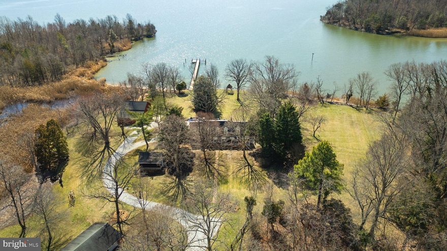 Rare Waterfront Opportunity! Escape to your waterfront farmhouse retreat. Nestled on 3.5 picturesque acres overlooking the tranquil waters of protected Moss Pond, this charming historic property offers big views of and direct access to the Chesapeake Bay. Originally part of a working thoroughbred racehorse farm, this home is surrounded by parkland and privacy while still close to the city. Imagine peaceful mornings, stunning sunsets, and the joys of waterfront living. Your dream of a serene coastal lifestyle awaits. Enjoy boating, fishing, birdwatching, and the peace and quiet of coastal living all just a short drive from all the history, charm and convenience Annapolis has to offer. A peaceful meandering drive leads you to this one of a kind property. Enjoy breathtaking water views from each of the 5 bedrooms or entertain family & friends in one of the many sitting rooms that have retained their original character and charm. Custom built ins, heart pine flooring and dual staircases to the upper level, this home is steeped in history. Ample waterside living with an enclosed porch with screens or glass offering year round use flowing perfectly to the patio overlooking your 287 feet of water frontage, the perfect place for summer cocktails and dinner parties! The property features three outbuildings, an enclosed barn that can accommodate 4 cars, a storage barn with horse stalls and a detached man cave that would make a perfect home office or studio! With a private pier, dock, boat and jetski lifts, you can enjoy all that the Chesapeake Bay has to offer. Whether you're looking for a peaceful retreat or a place to entertain family and friends, this farmhouse is the perfect place. Welcome Home!